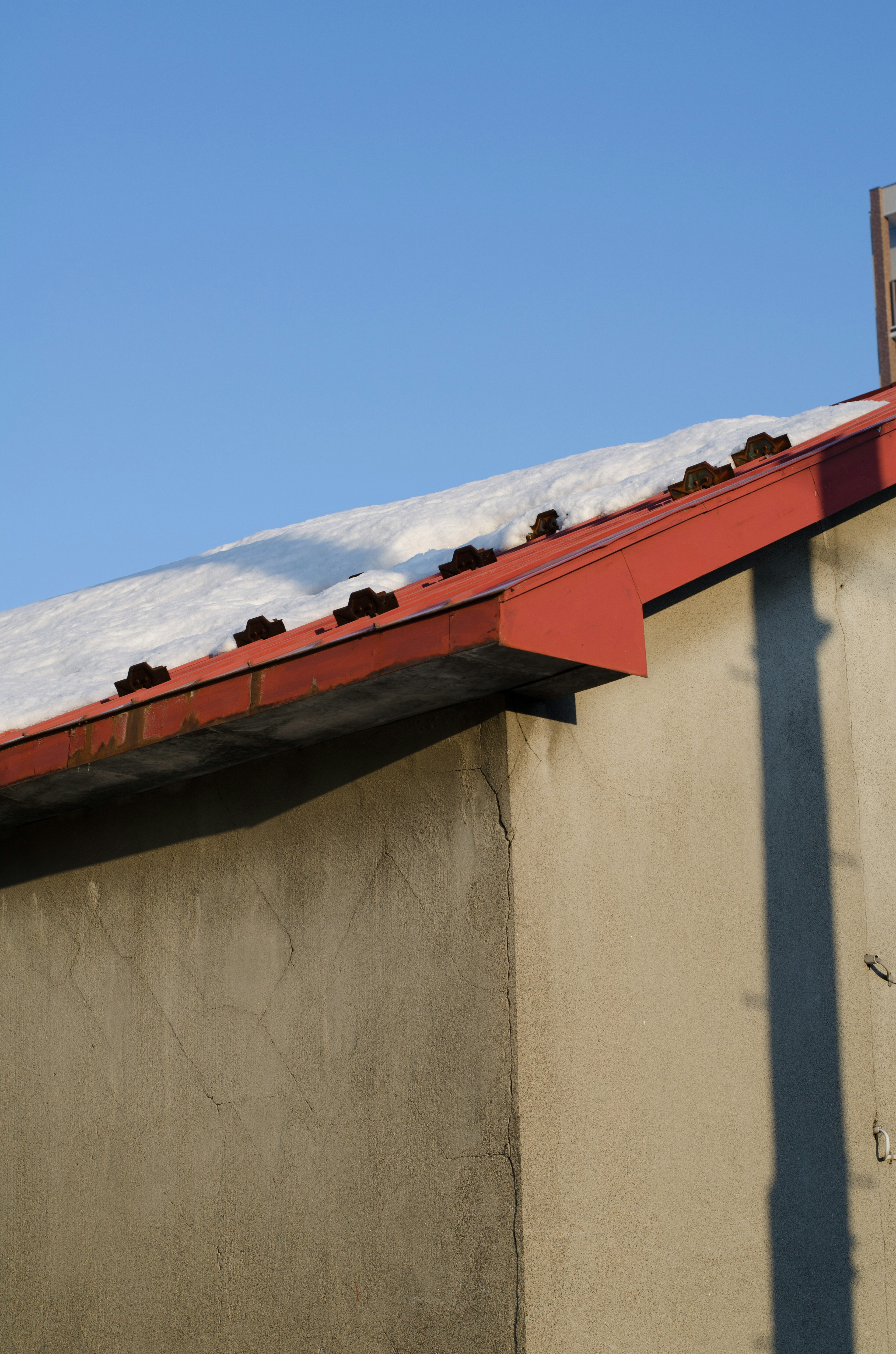 Photo of a red roof with snow and a clear blue sky