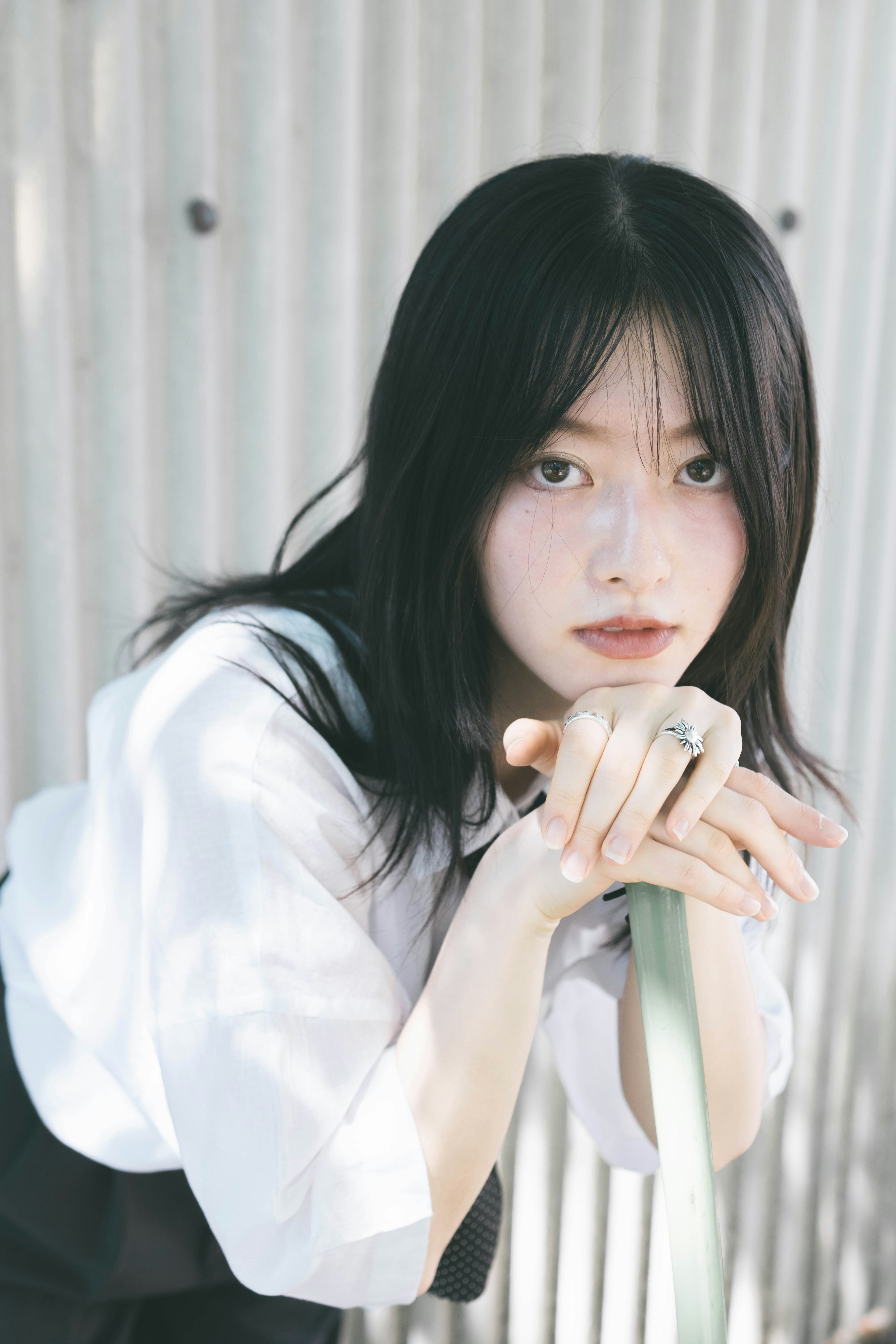 Portrait of a woman wearing a white shirt with black hair resting her hands