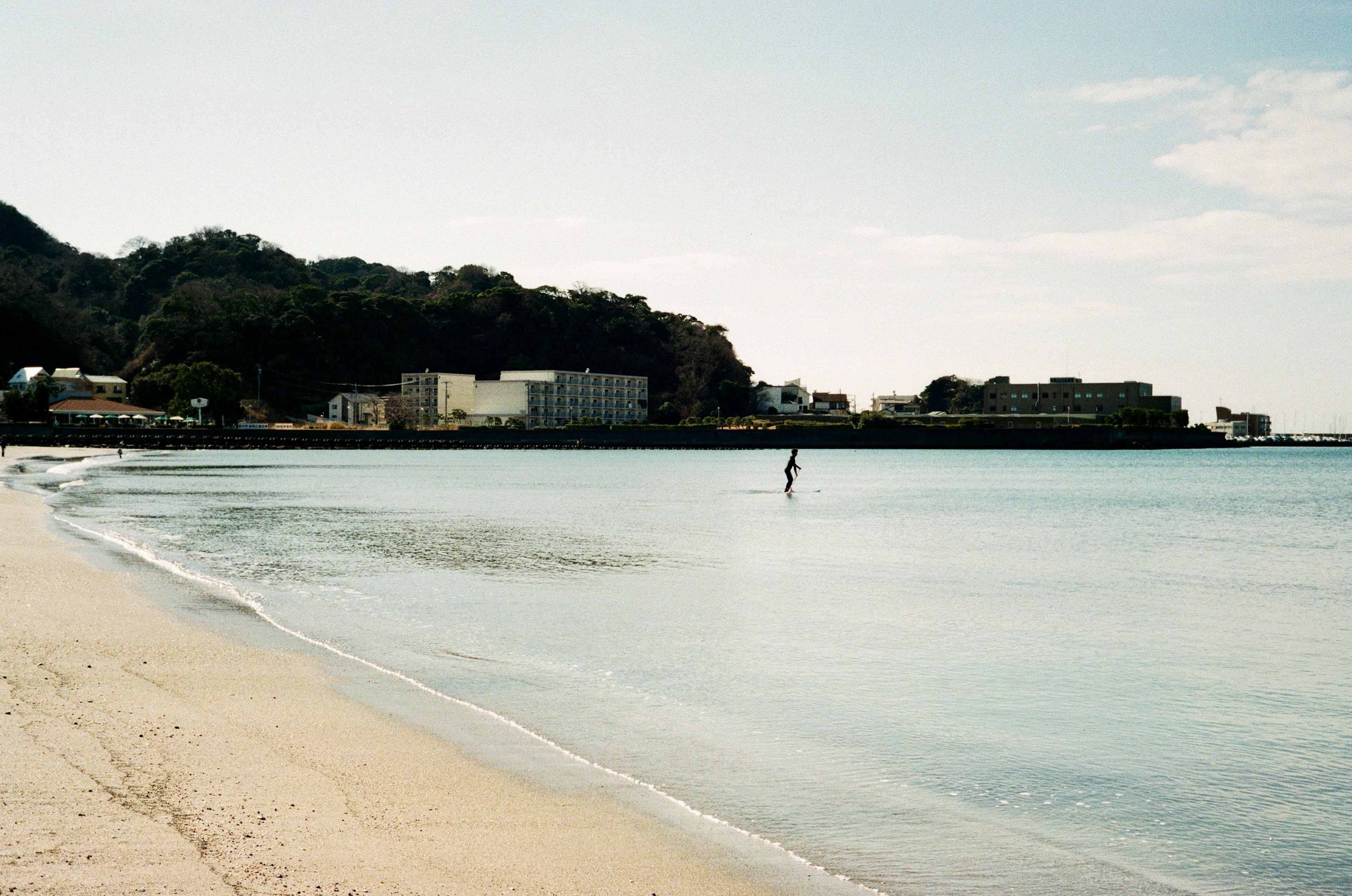 Una scena di spiaggia tranquilla con una persona in piedi nell'acqua