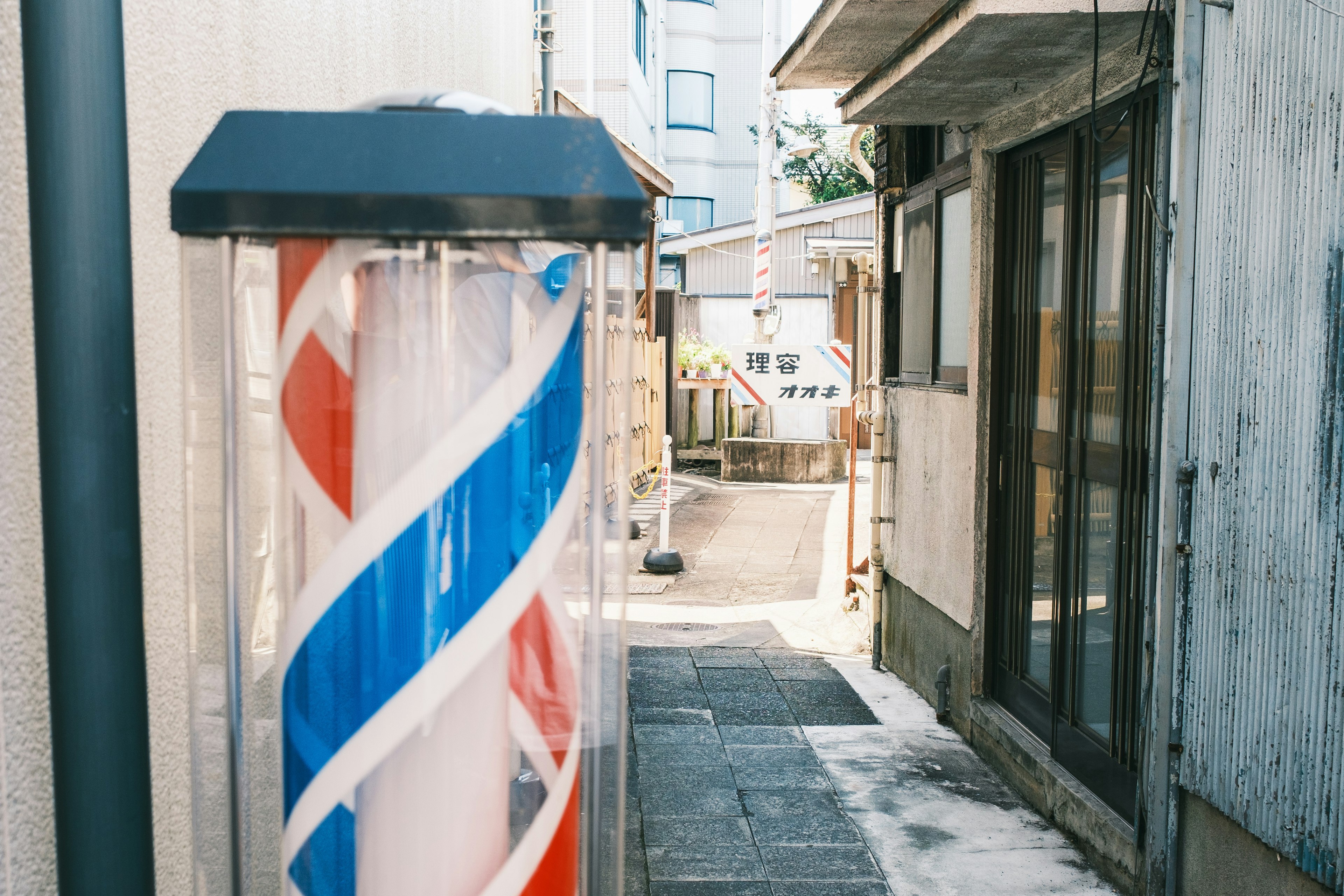 Narrow alley featuring a barber shop sign with red and blue stripes