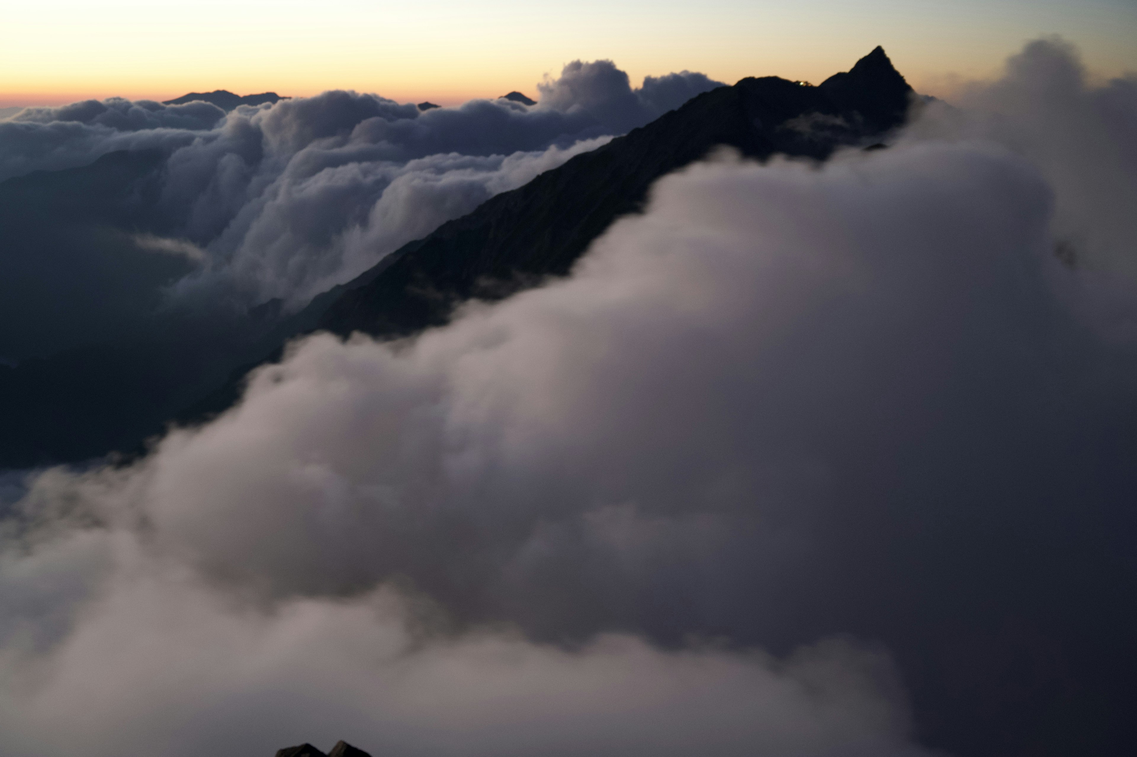 Silueta de una montaña cubierta de nubes con un cielo al atardecer