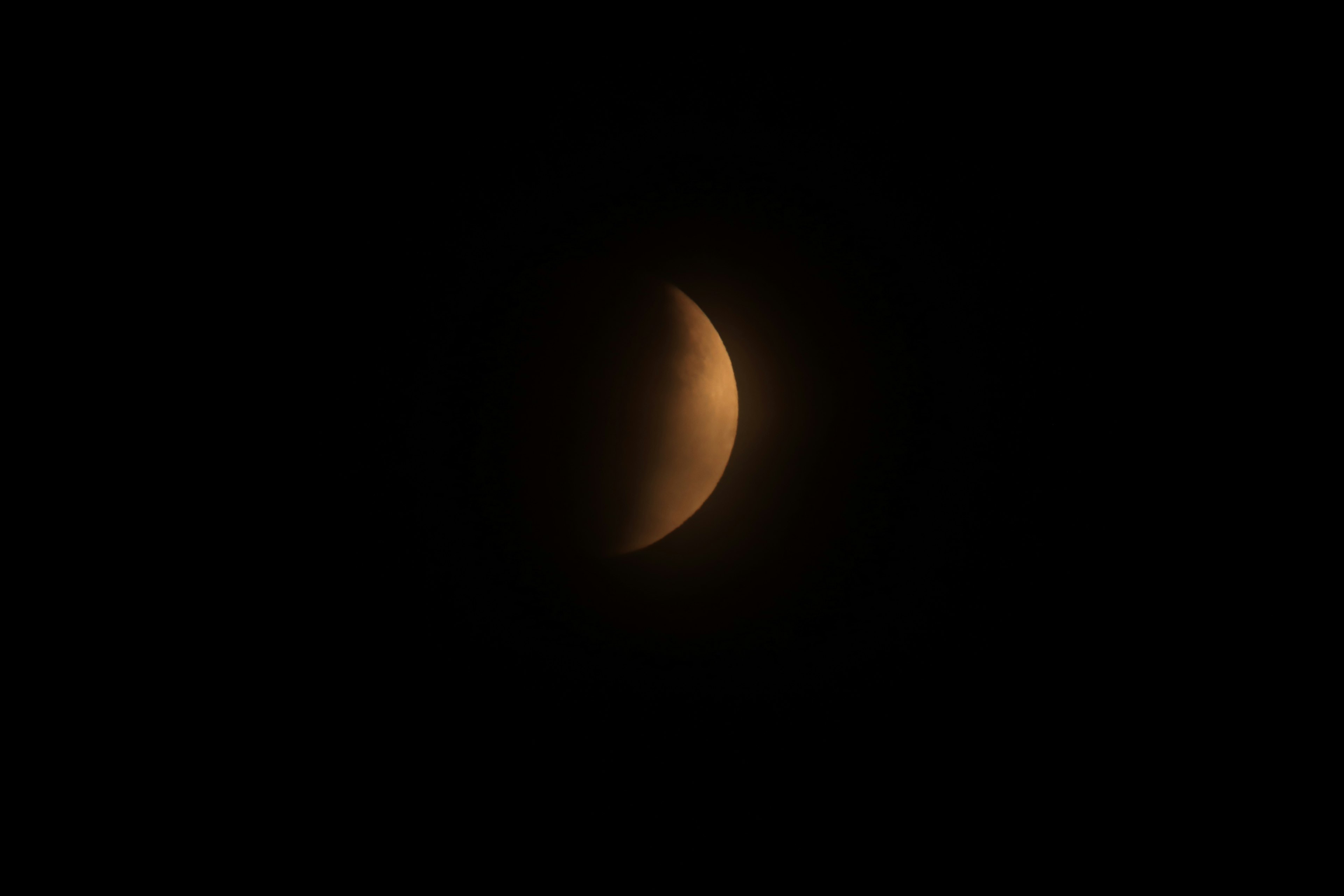 Una luna creciente de color naranja contra un fondo oscuro