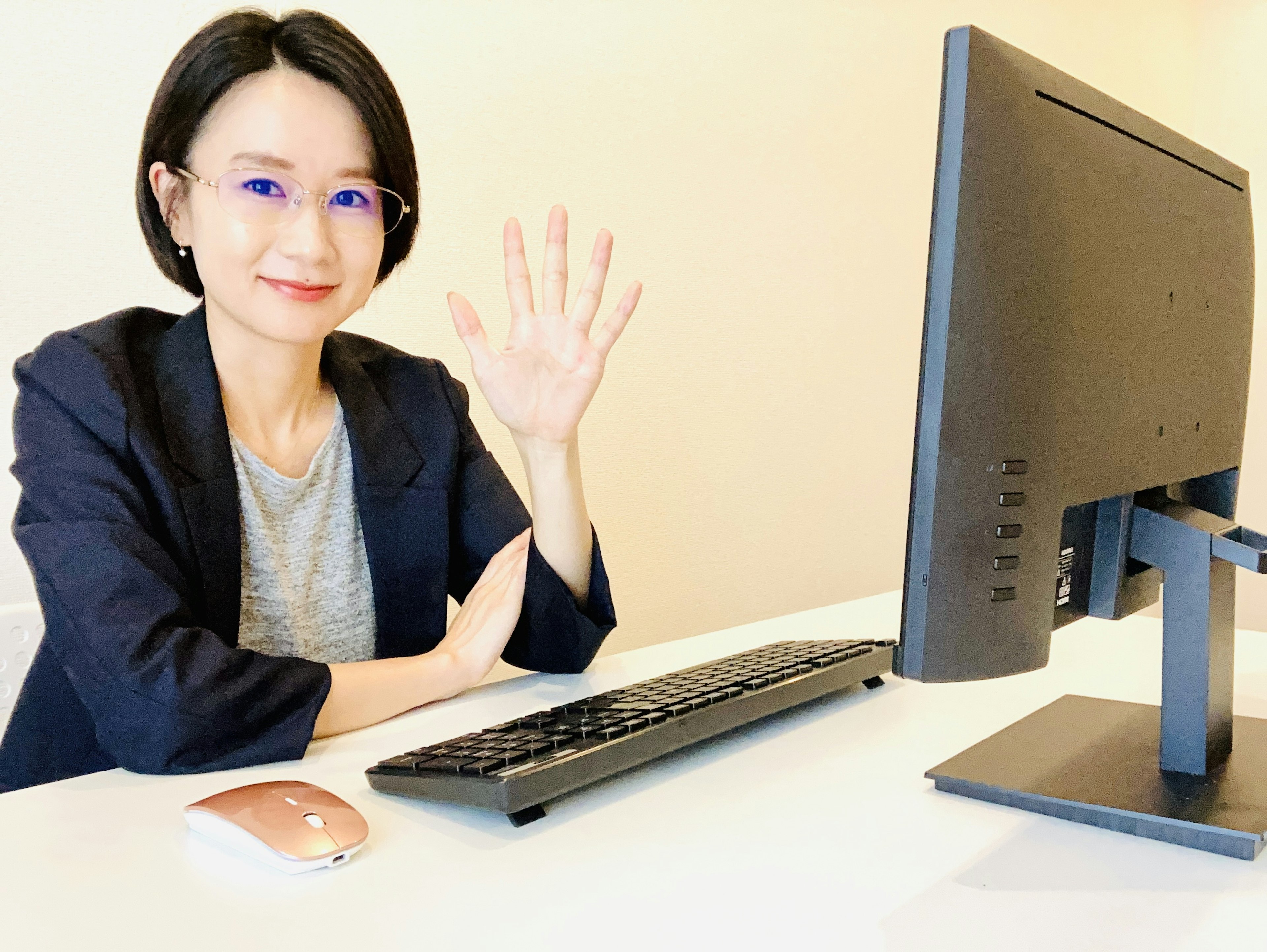 Mujer saludando a una computadora mientras está sentada en un escritorio