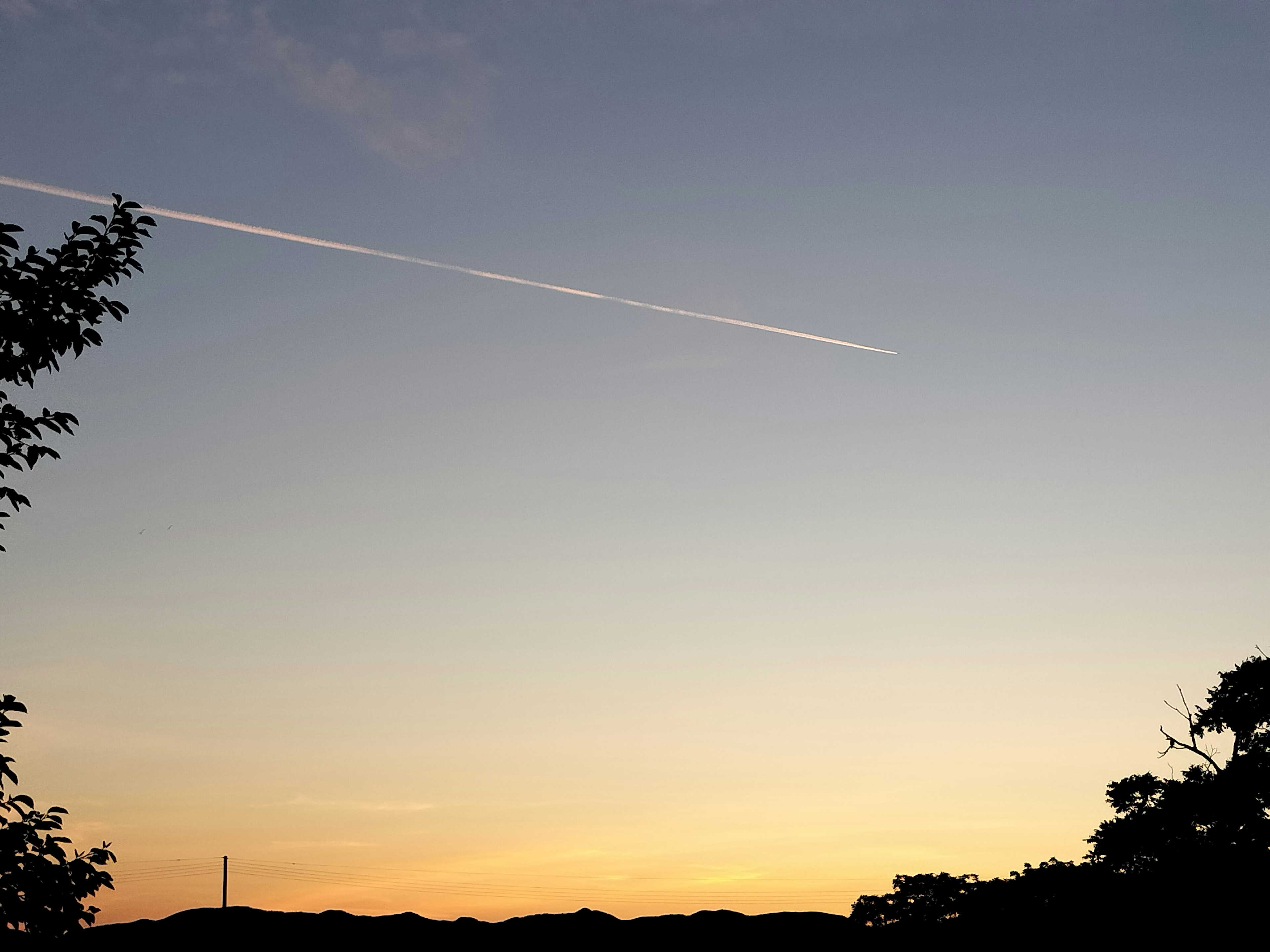 夕焼けの空に飛行機雲が見える風景