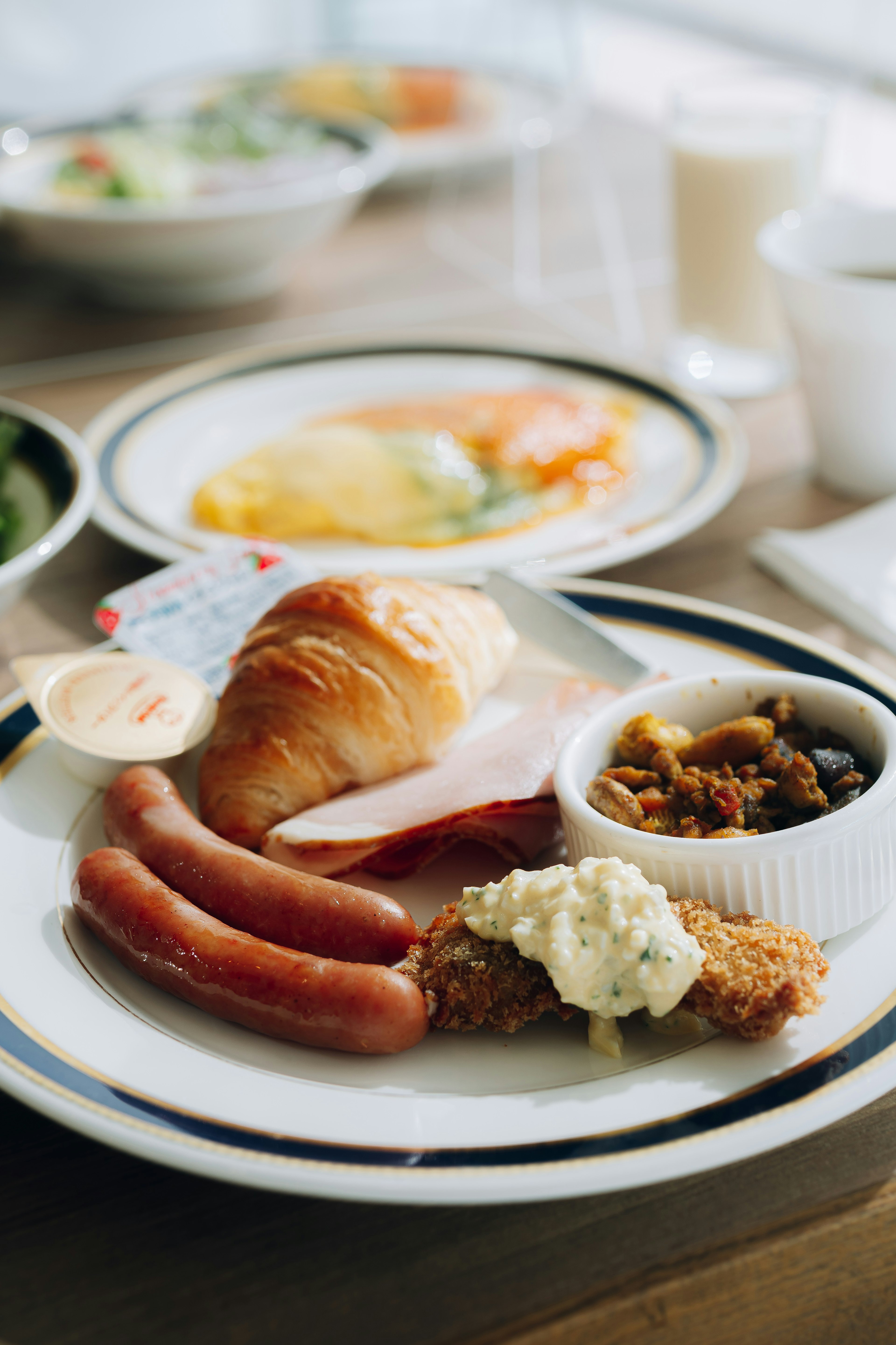 Breakfast plate with sausages croissant salad yogurt omelette