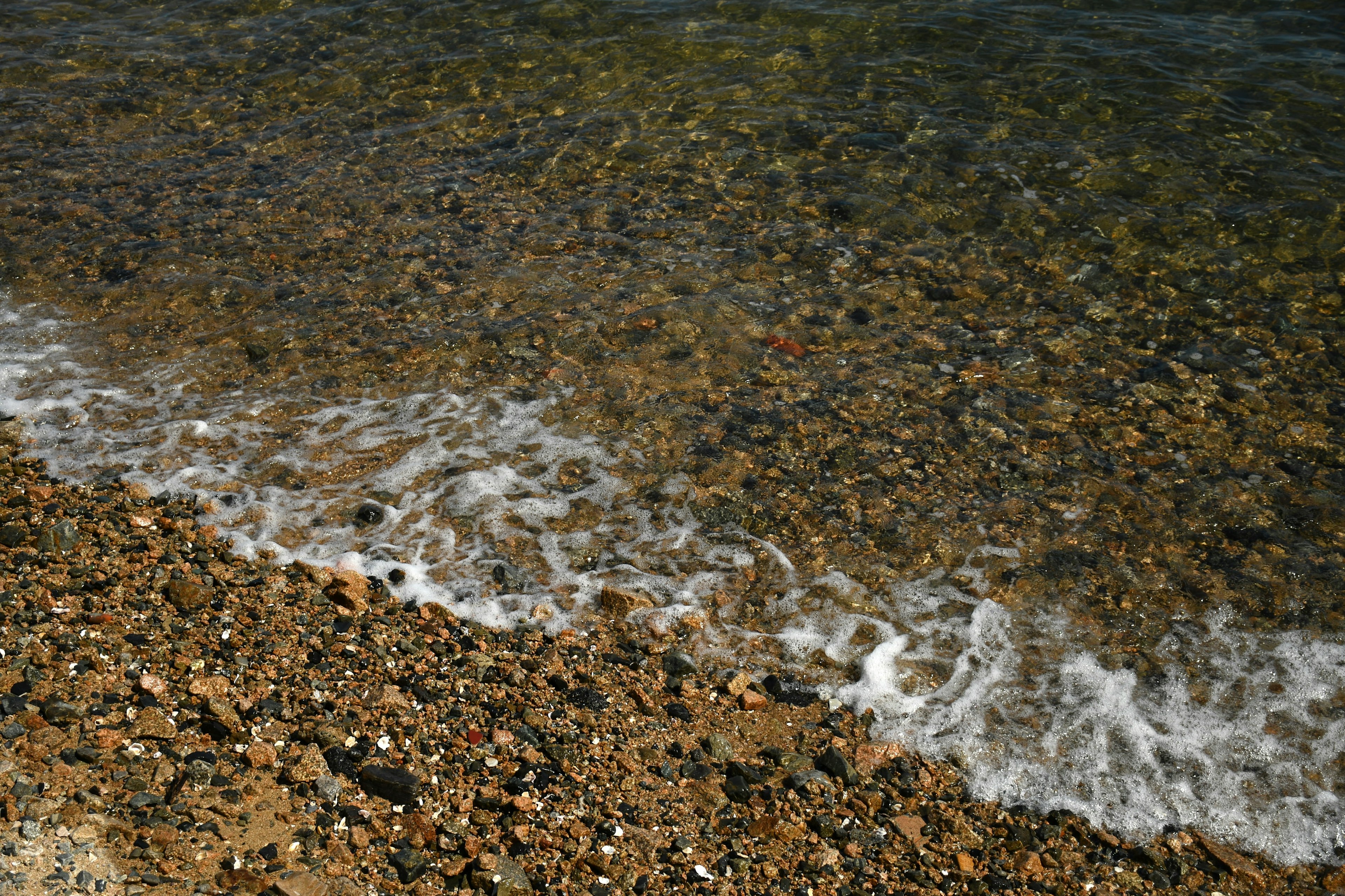 Image de galets et de douces vagues au bord de l'eau