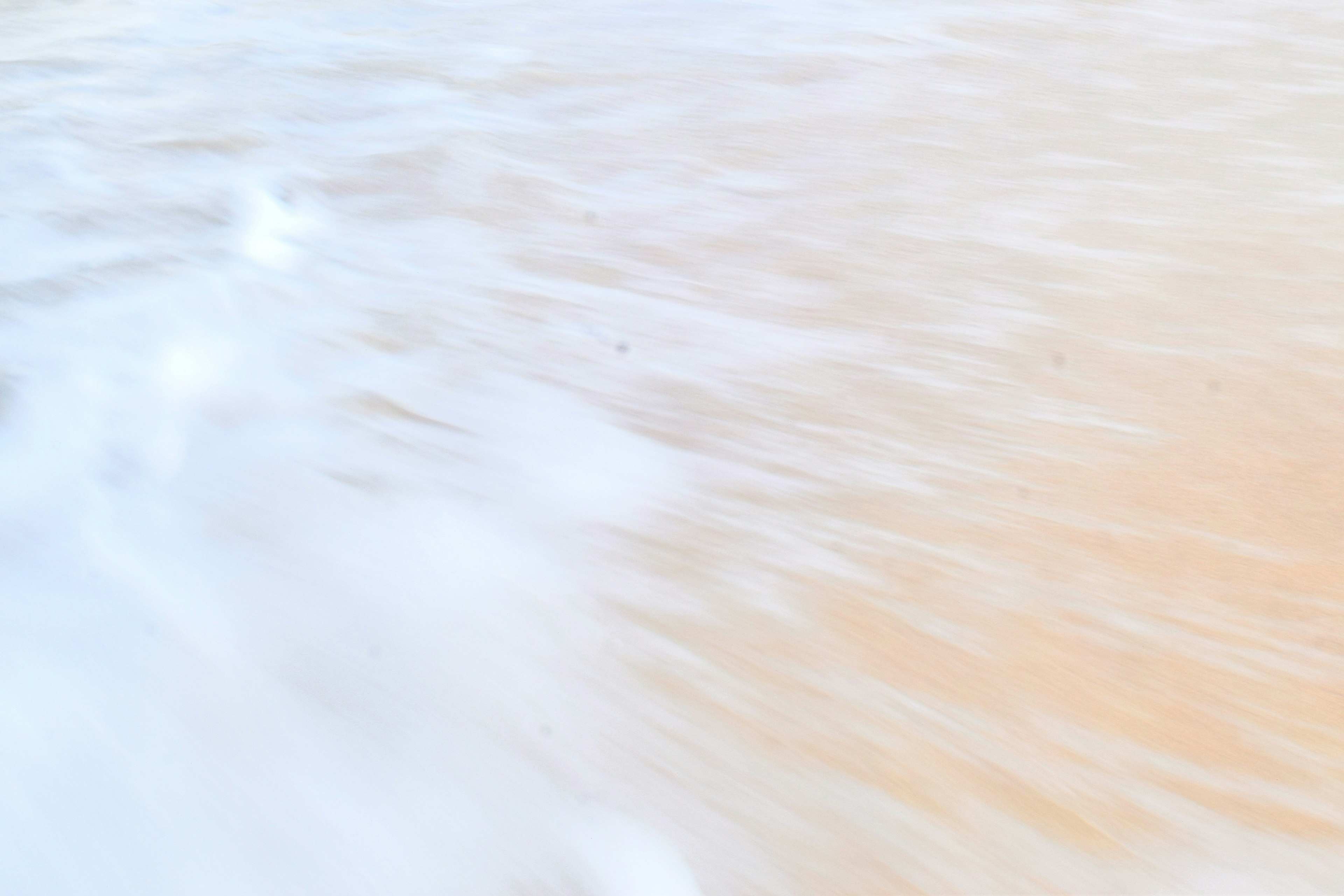 Abstract image of flowing water with soft orange and white hues