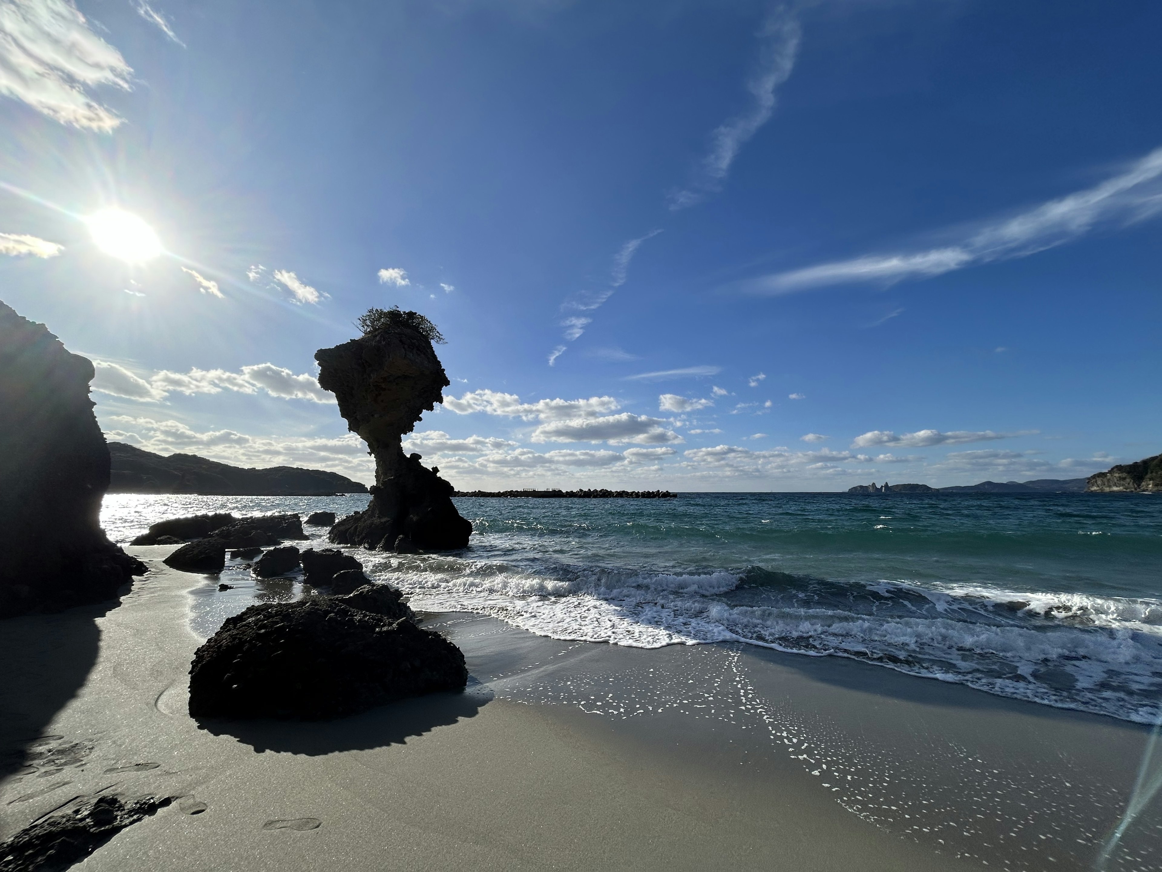 Coastal scene featuring a unique rock formation and blue sky