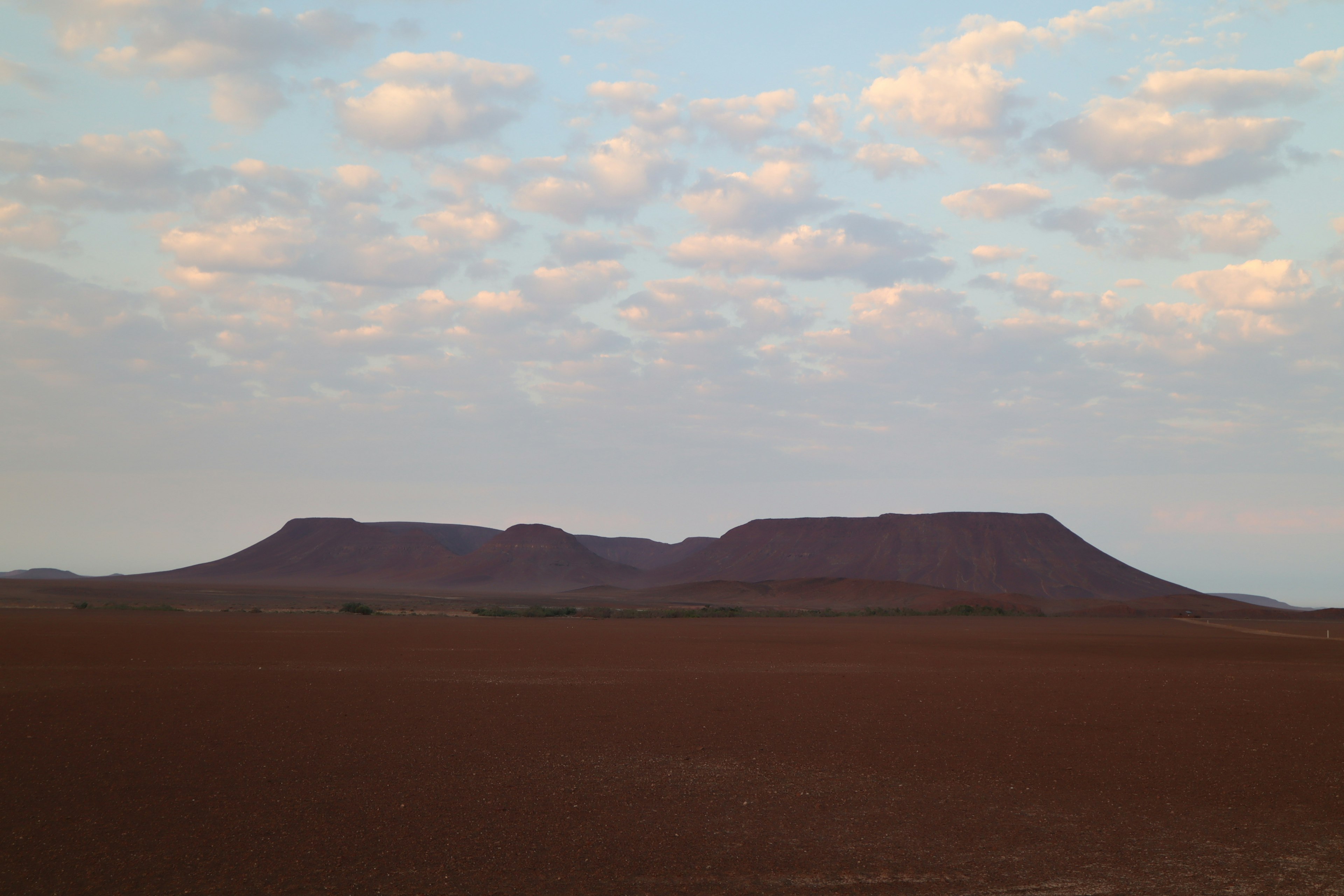 Silhouette de deux montagnes s'élevant au-dessus d'une vaste plaine sous un ciel calme