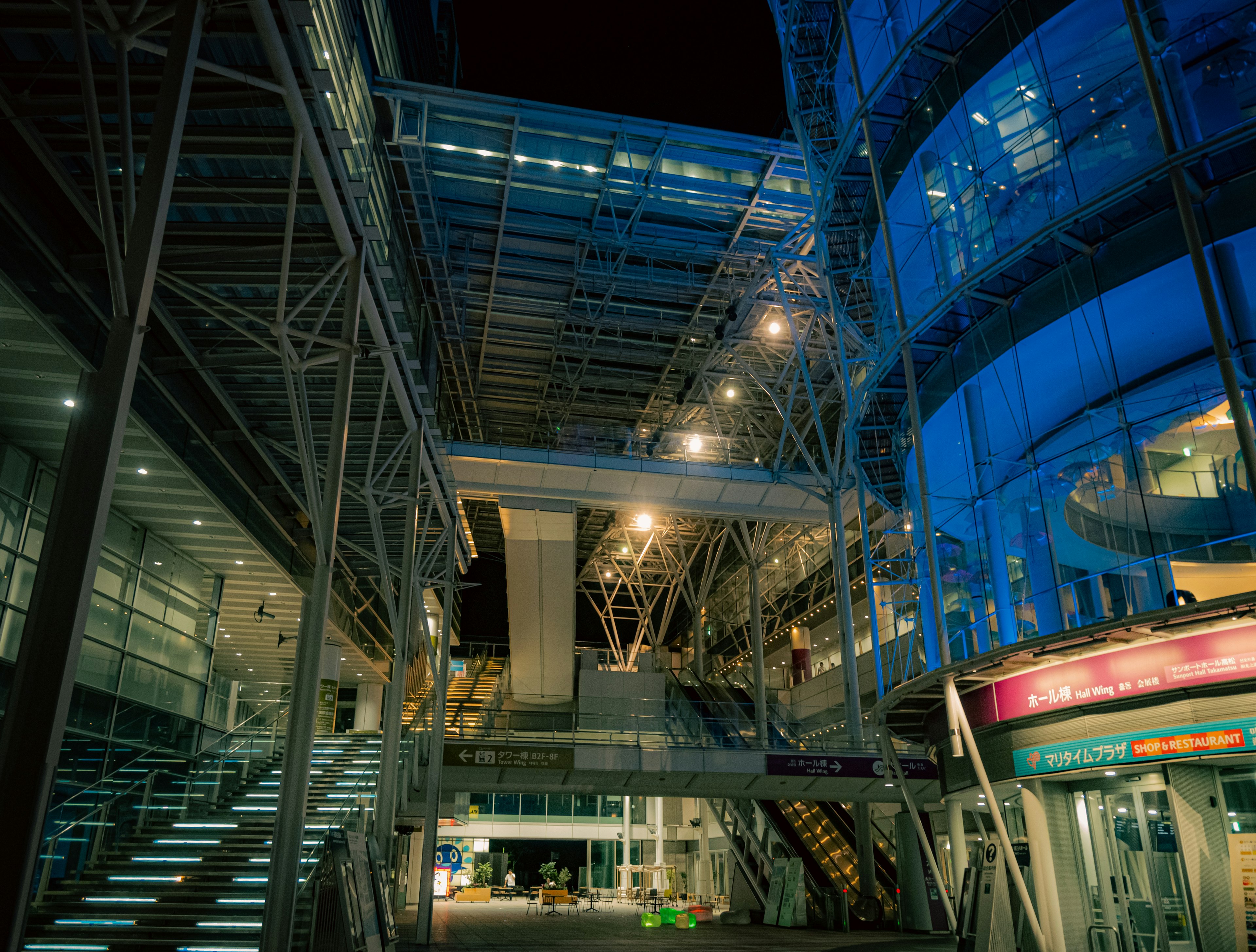 Intérieur d'un bâtiment moderne la nuit avec des structures métalliques complexes et un éclairage lumineux