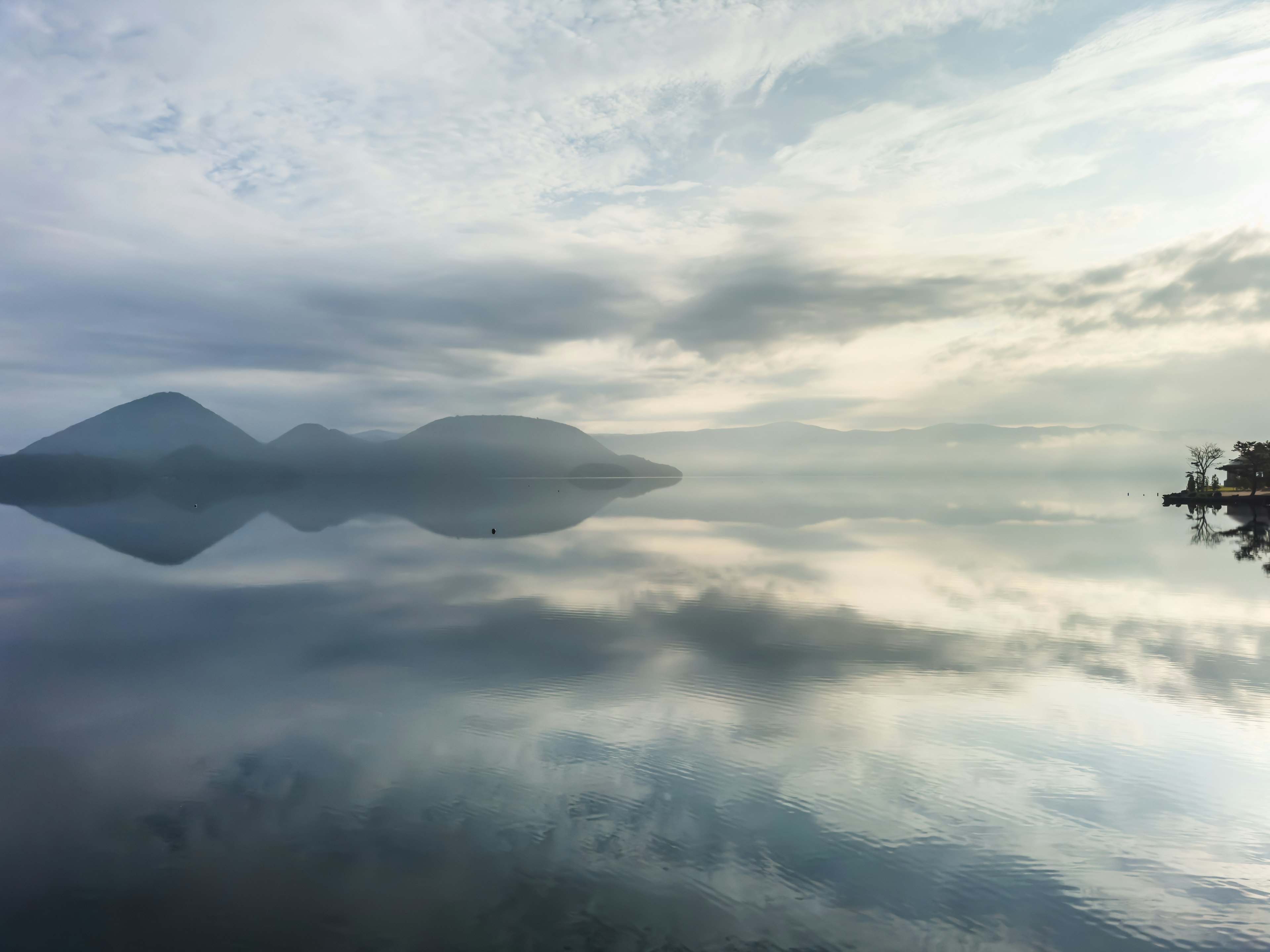 Pemandangan tenang gunung dan awan yang terpantul di danau tenang