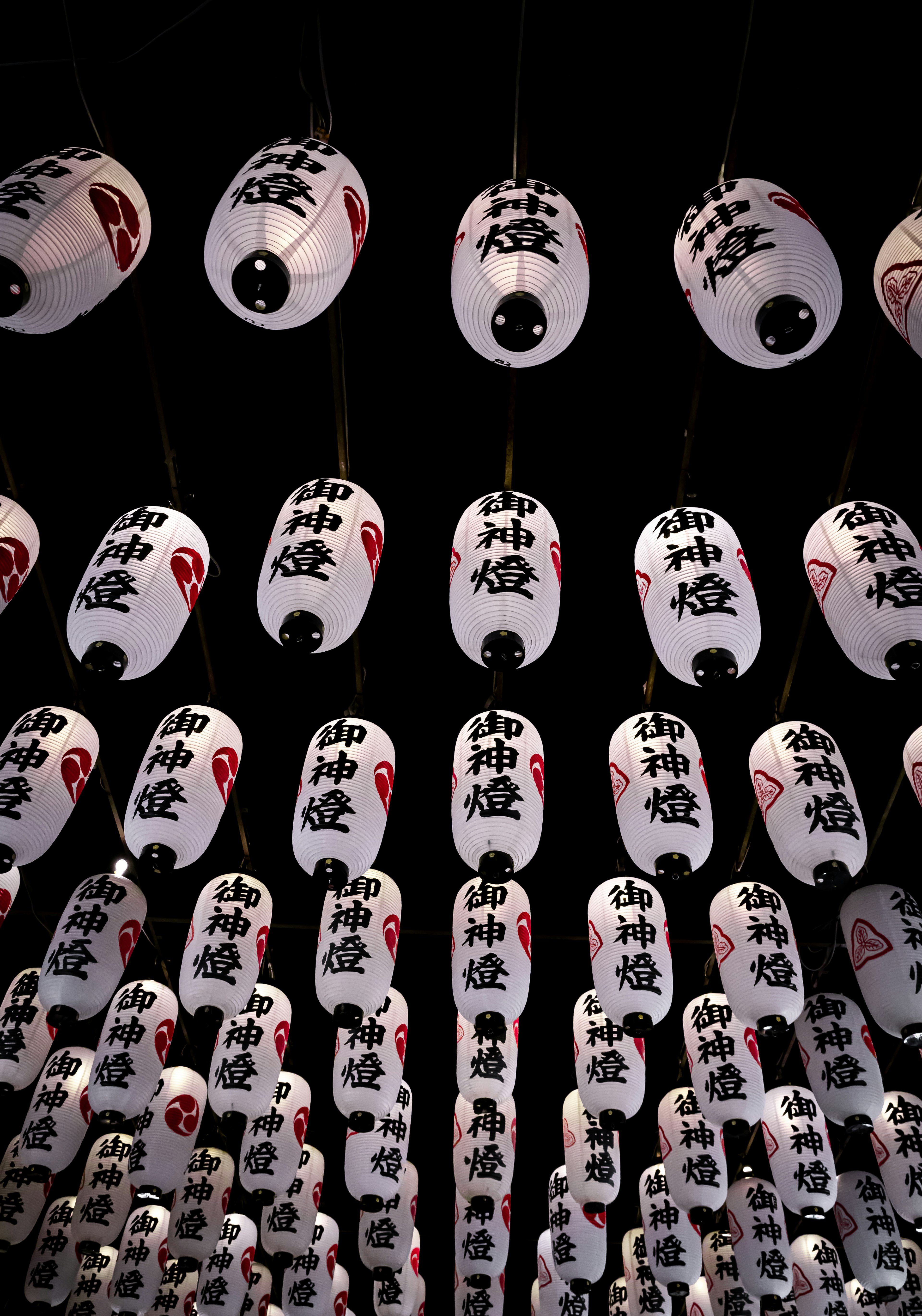 Lampions blancs avec des motifs rouges suspendus sur un fond sombre