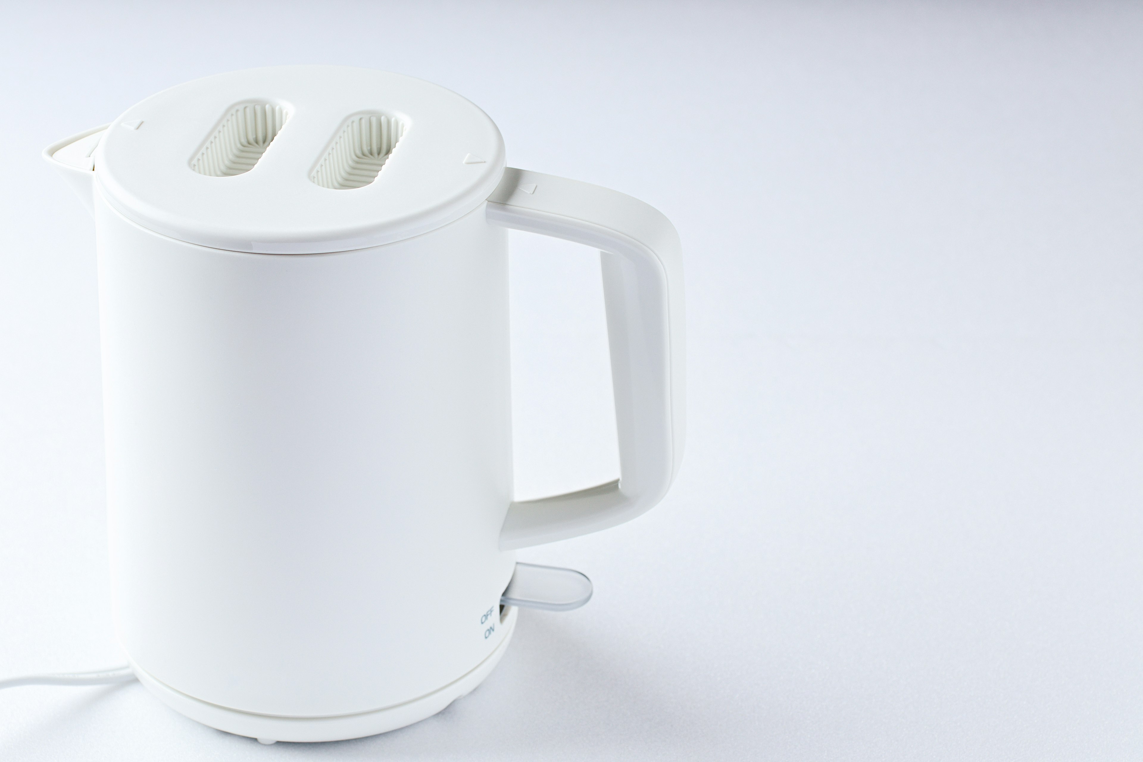 A white electric kettle is placed on a table