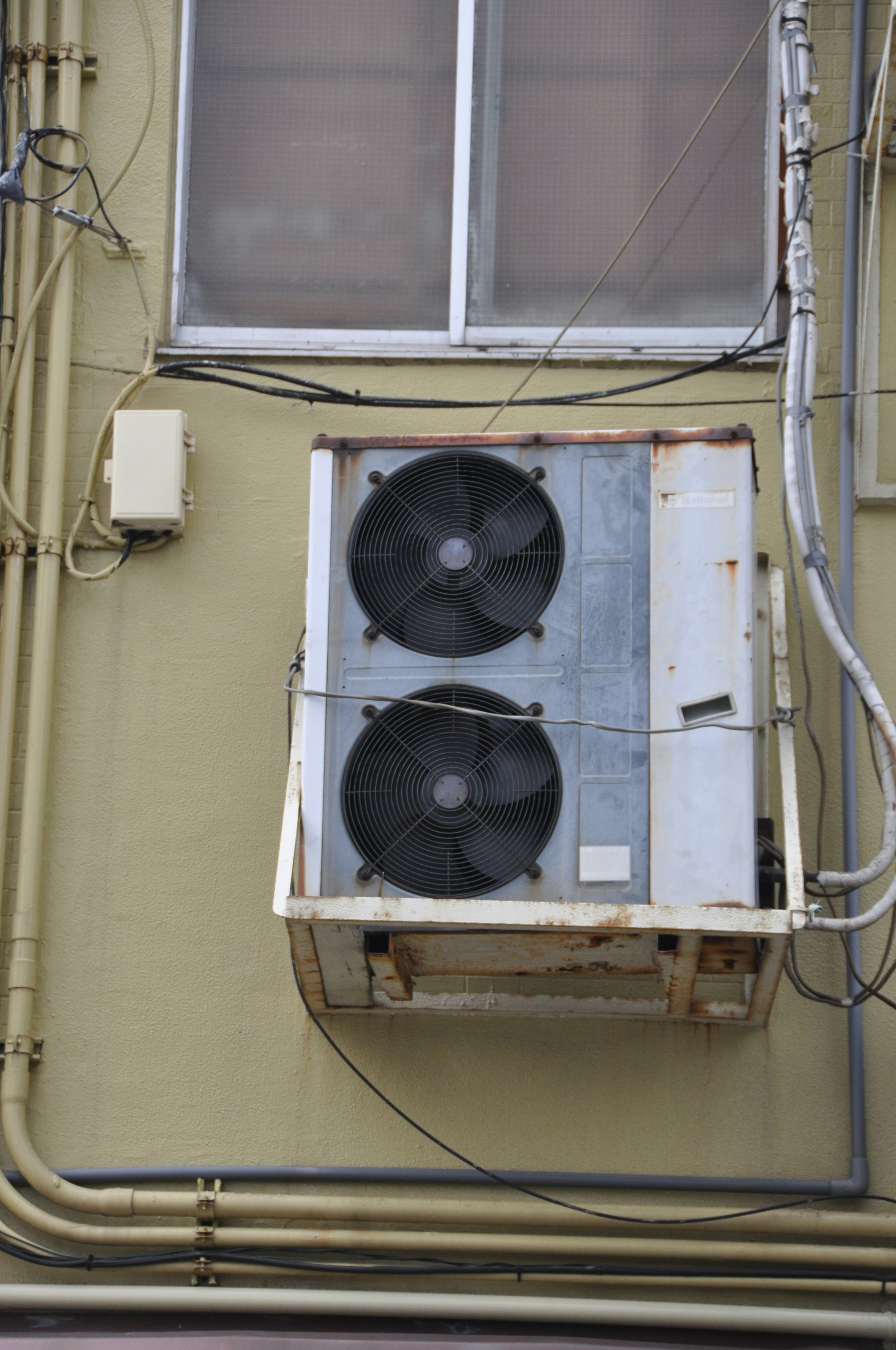 Air conditioning unit mounted on an exterior wall with visible wiring