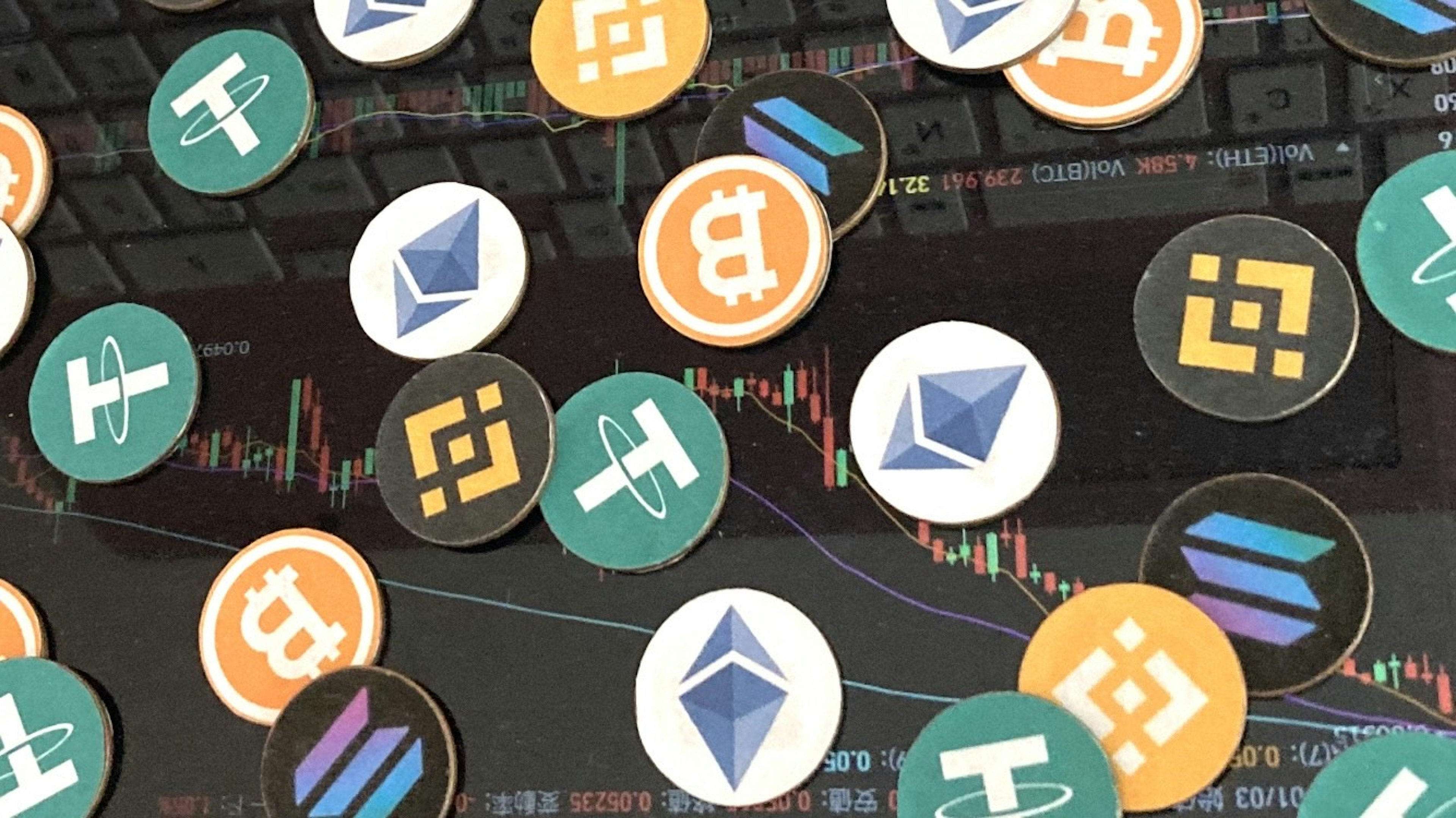 Diverse monete di criptovaluta tra cui Bitcoin ed Ethereum sparse su un grafico dei prezzi