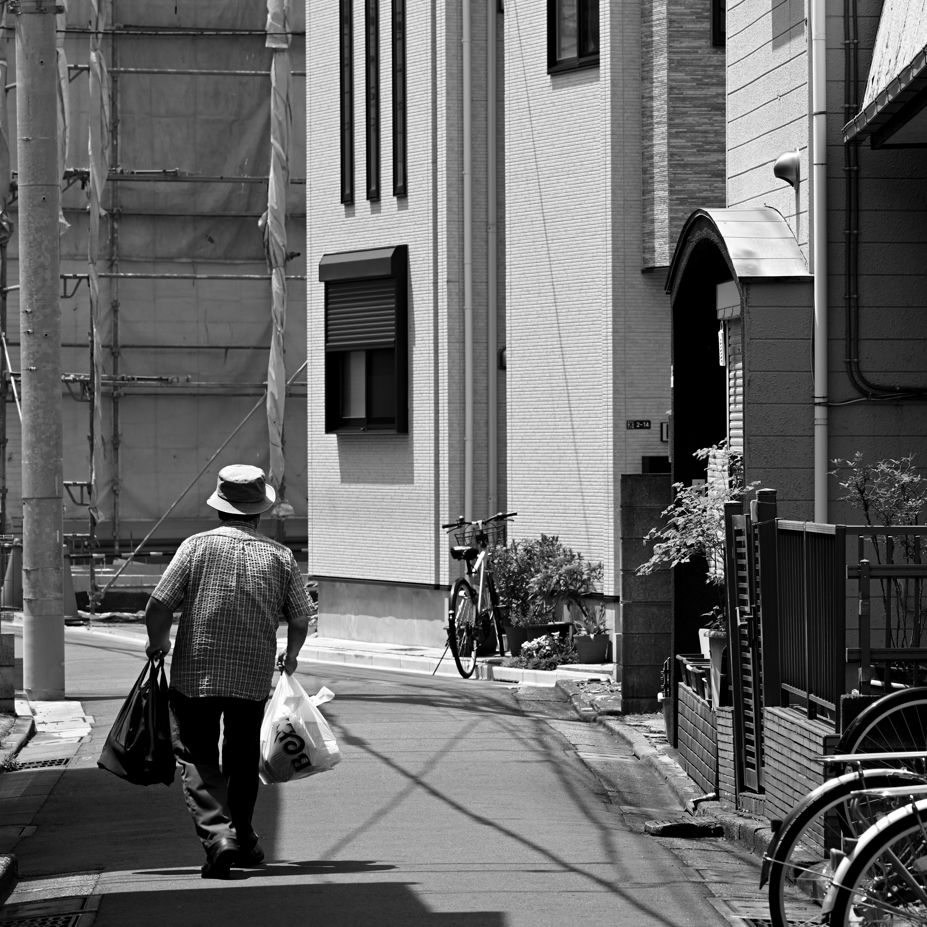 Un hombre caminando con bolsas de compras en una escena de calle en blanco y negro