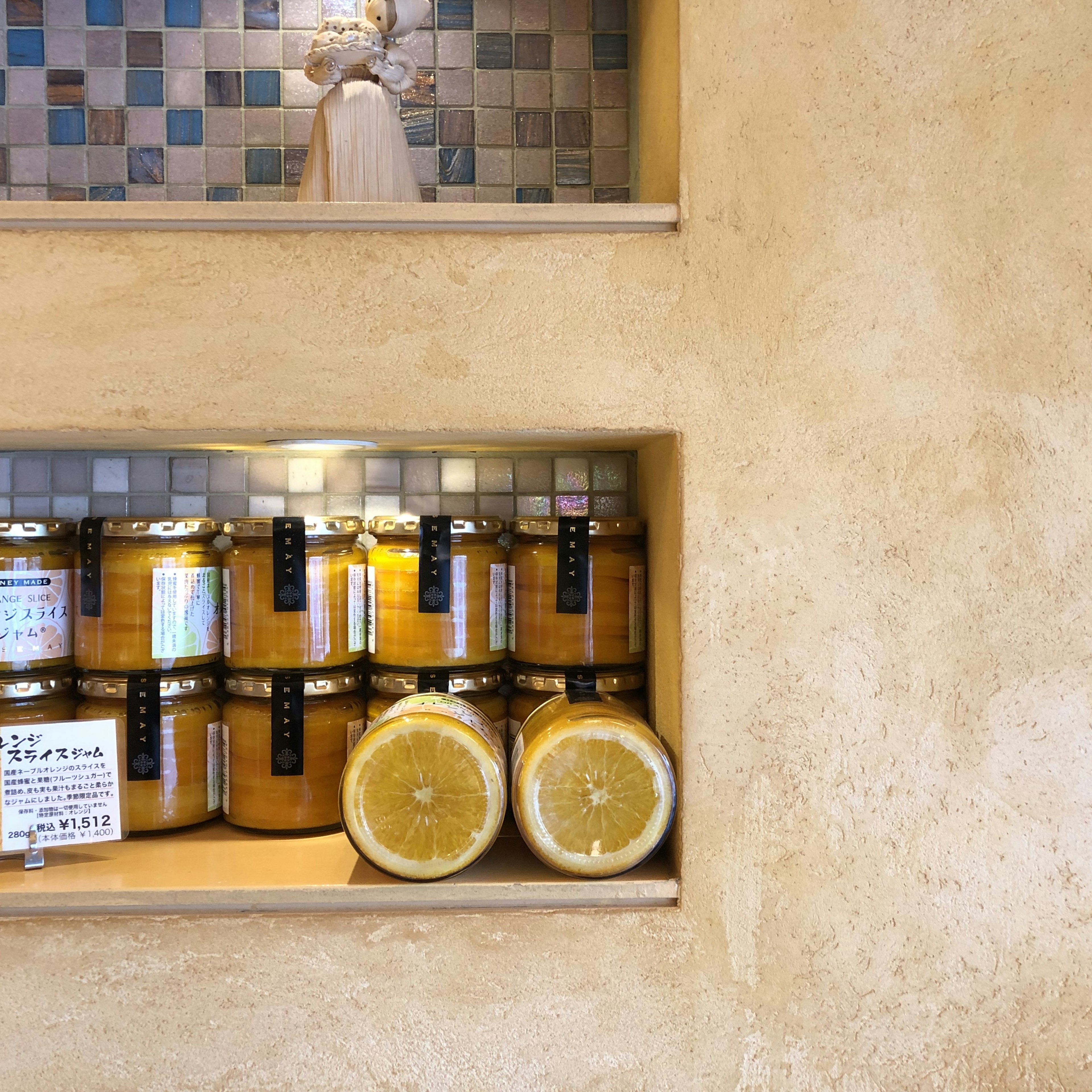 Shelves displaying jars of jam and sliced lemons in a warm interior