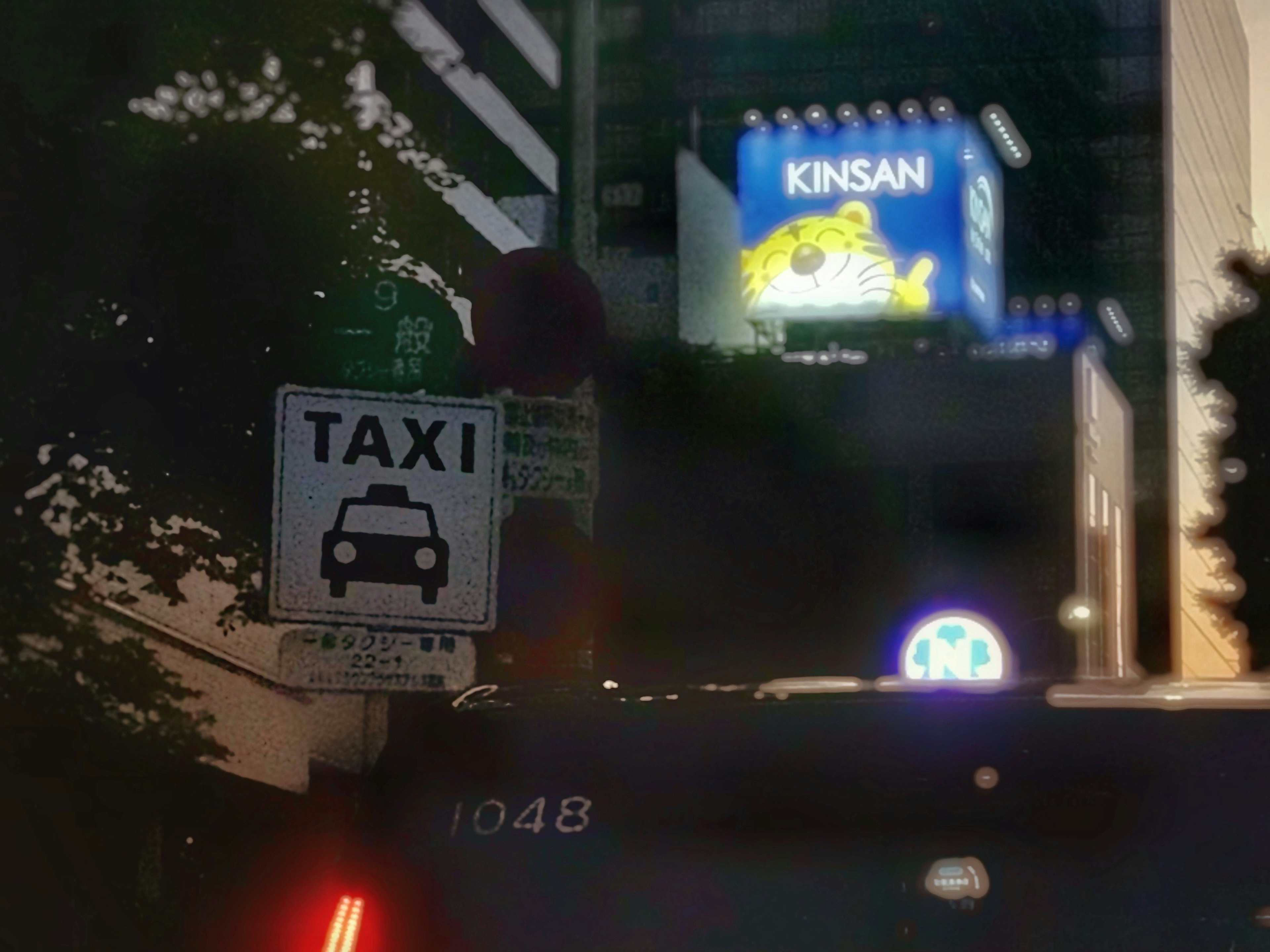 Escena urbana con un letrero de taxi y una cartelera iluminada por la noche