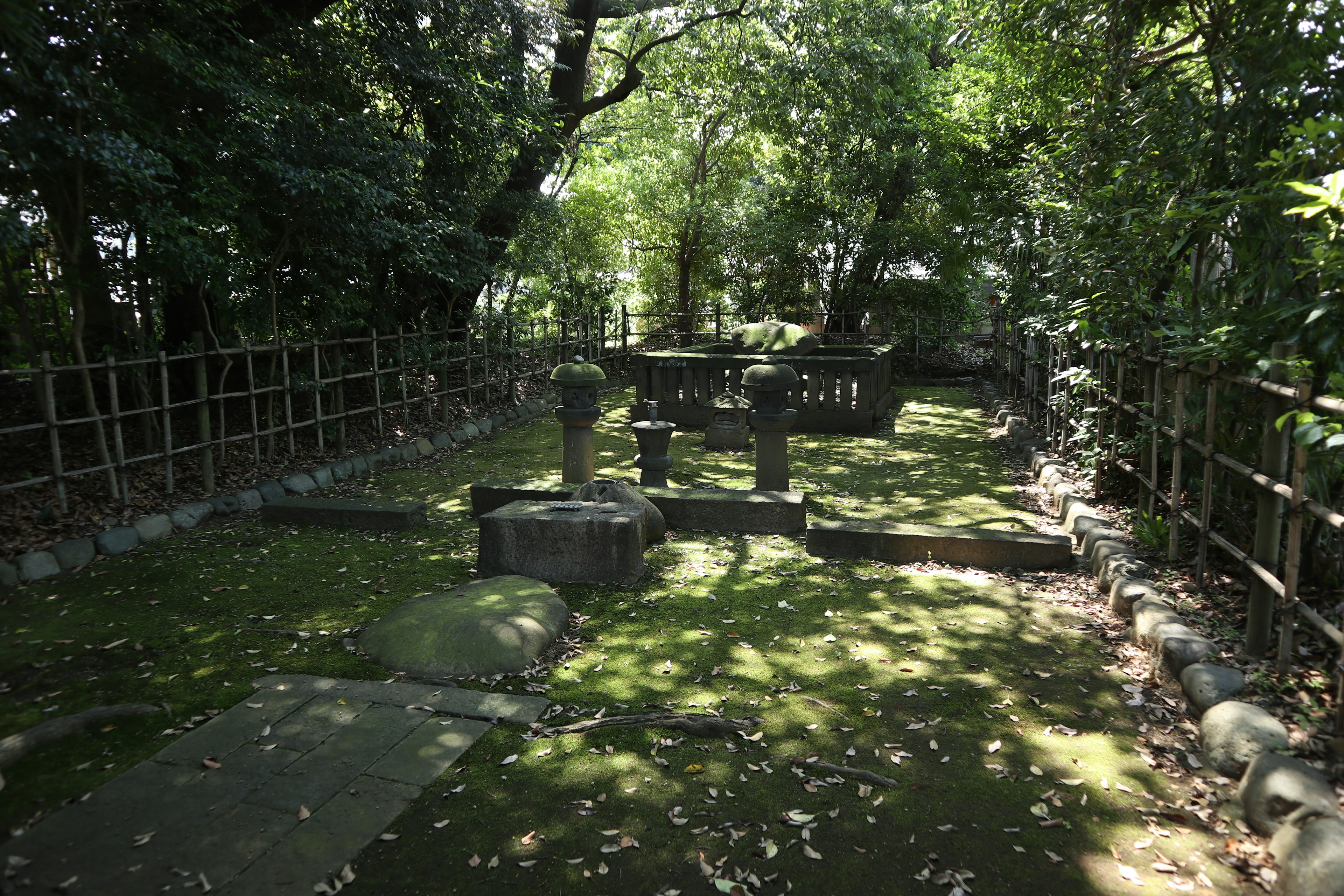 Sebuah makam batu tua di taman hijau yang subur