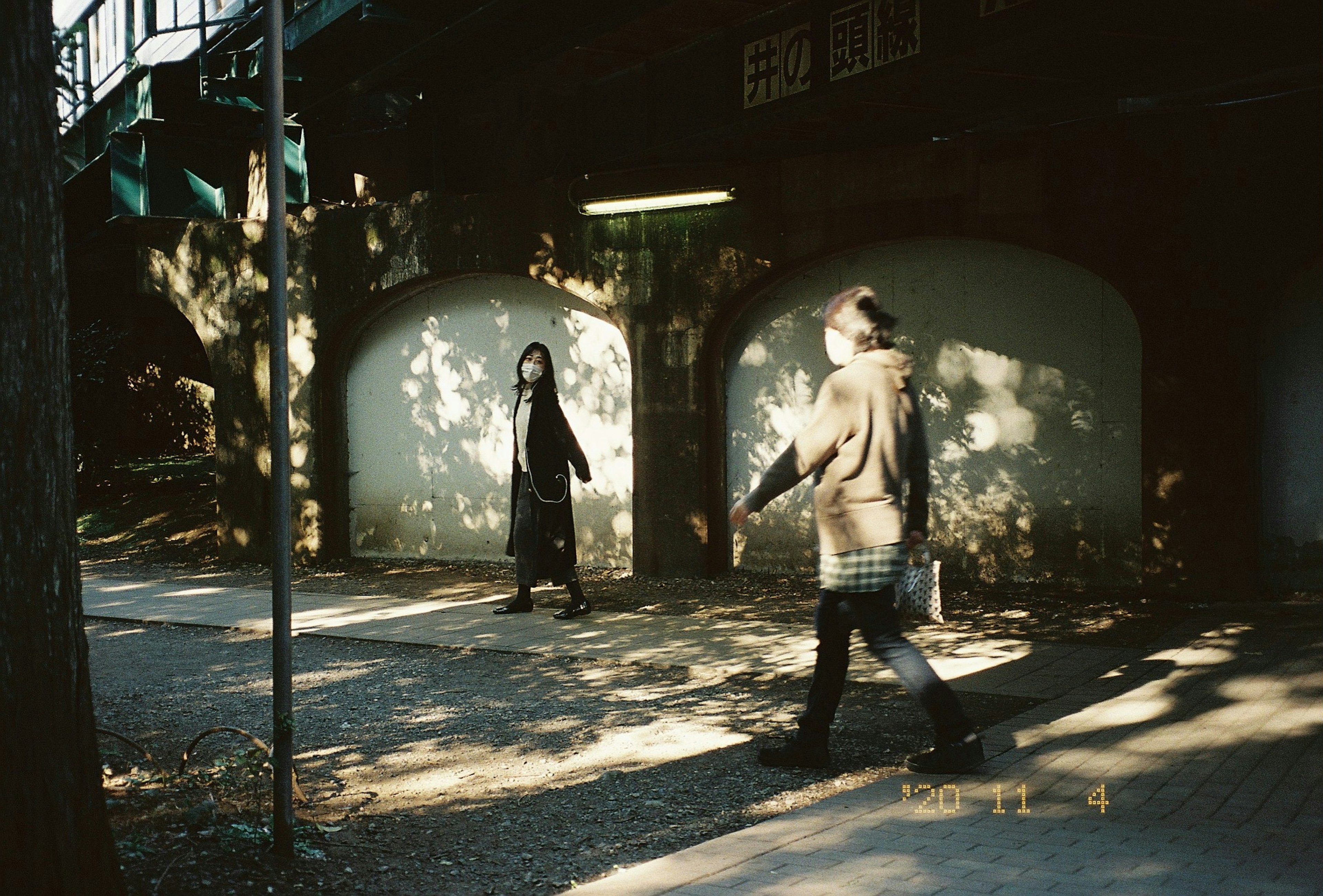 Dos figuras caminando por un sendero del parque con impresionantes contrastes de luz y sombra