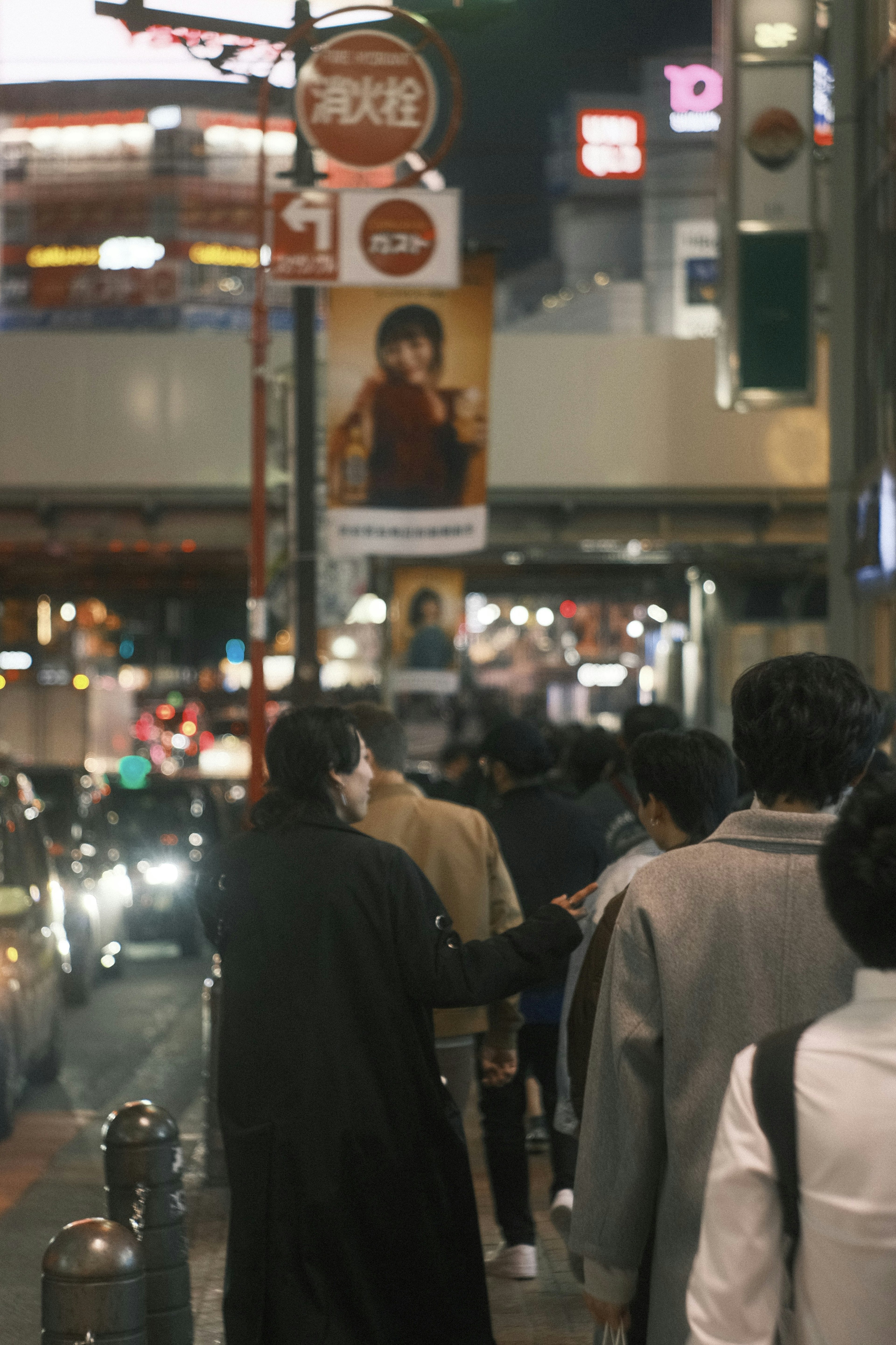 都市の夜の通りを歩く人々と明るい看板が見える