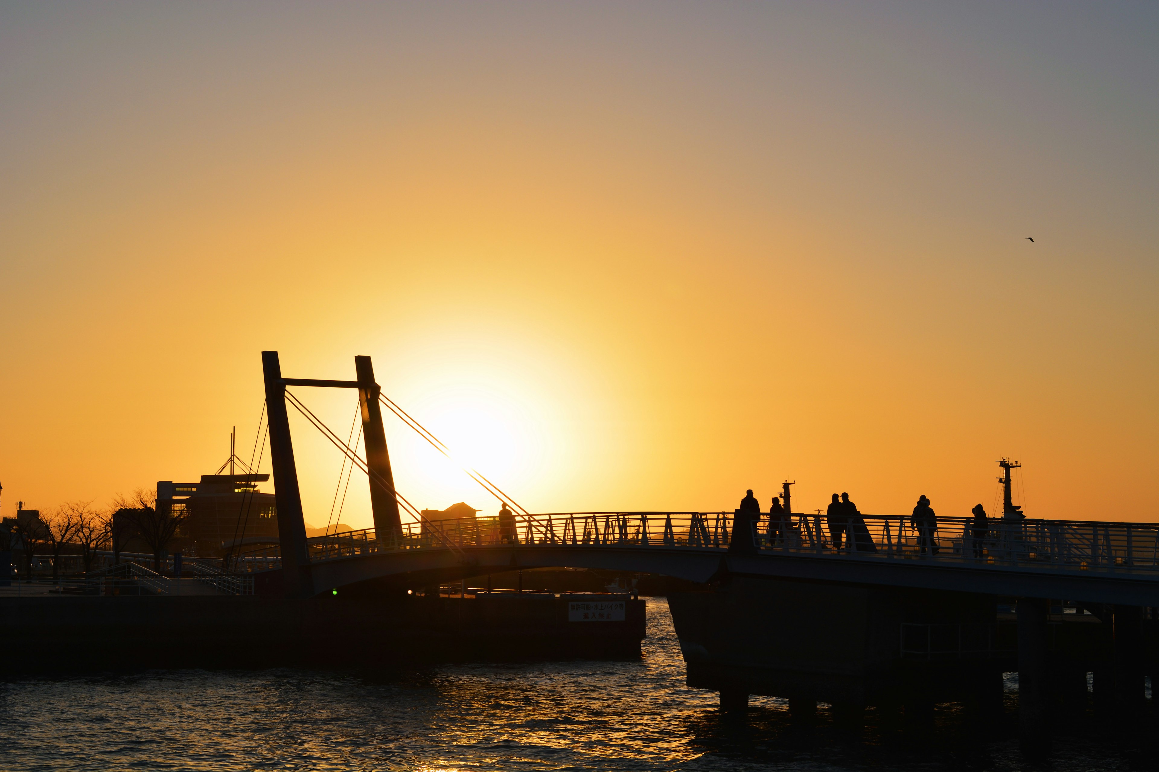 Bridge silhouetted against a sunset with people walking