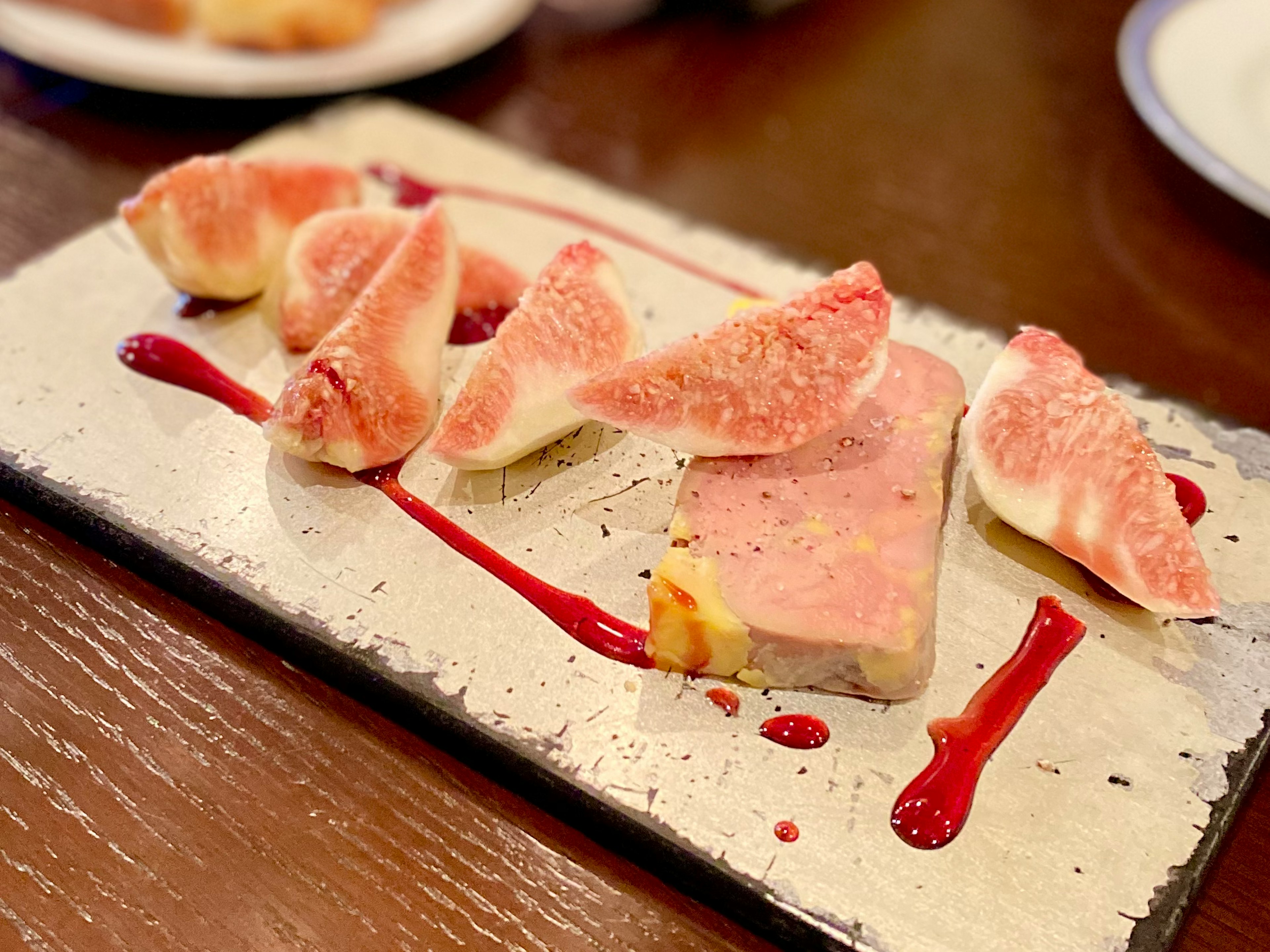 Ein Gericht mit cremigem pâté, garniert mit frischen Feigen und beträufelt mit Beerensoße