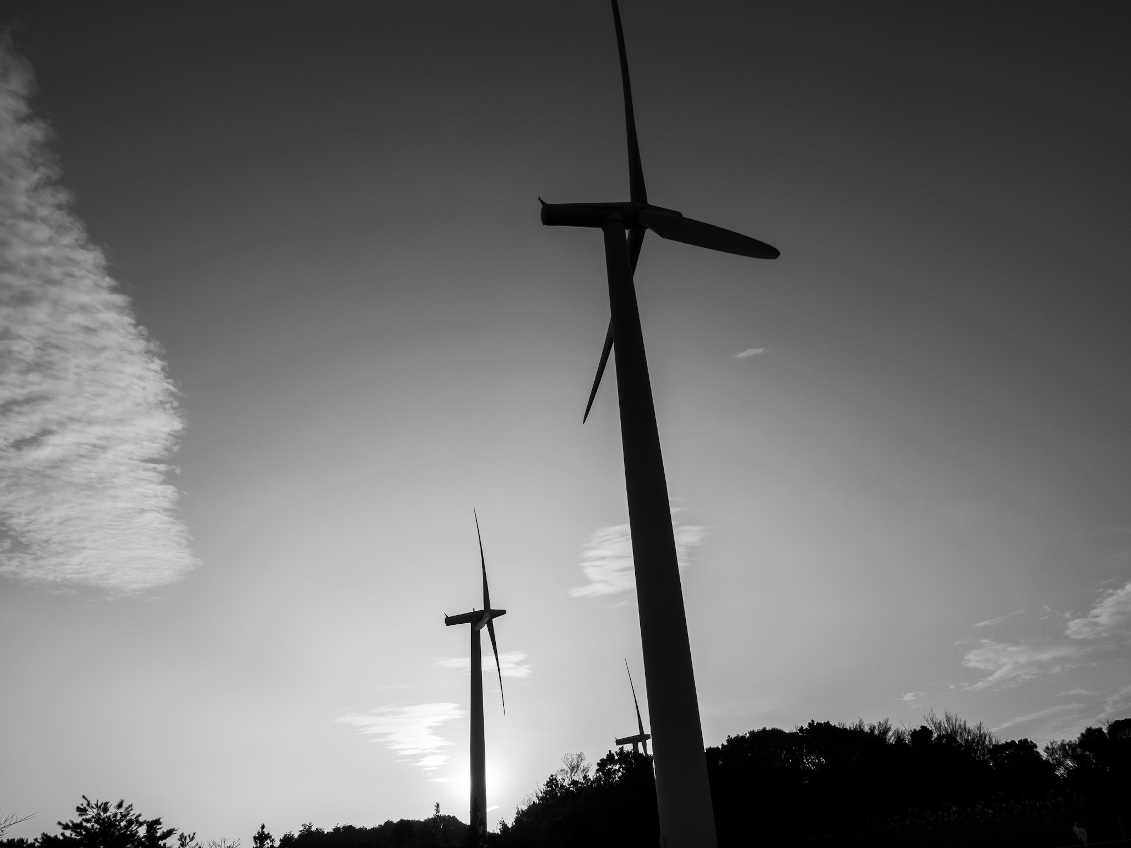 Silhouette d'éoliennes contre un ciel au coucher du soleil