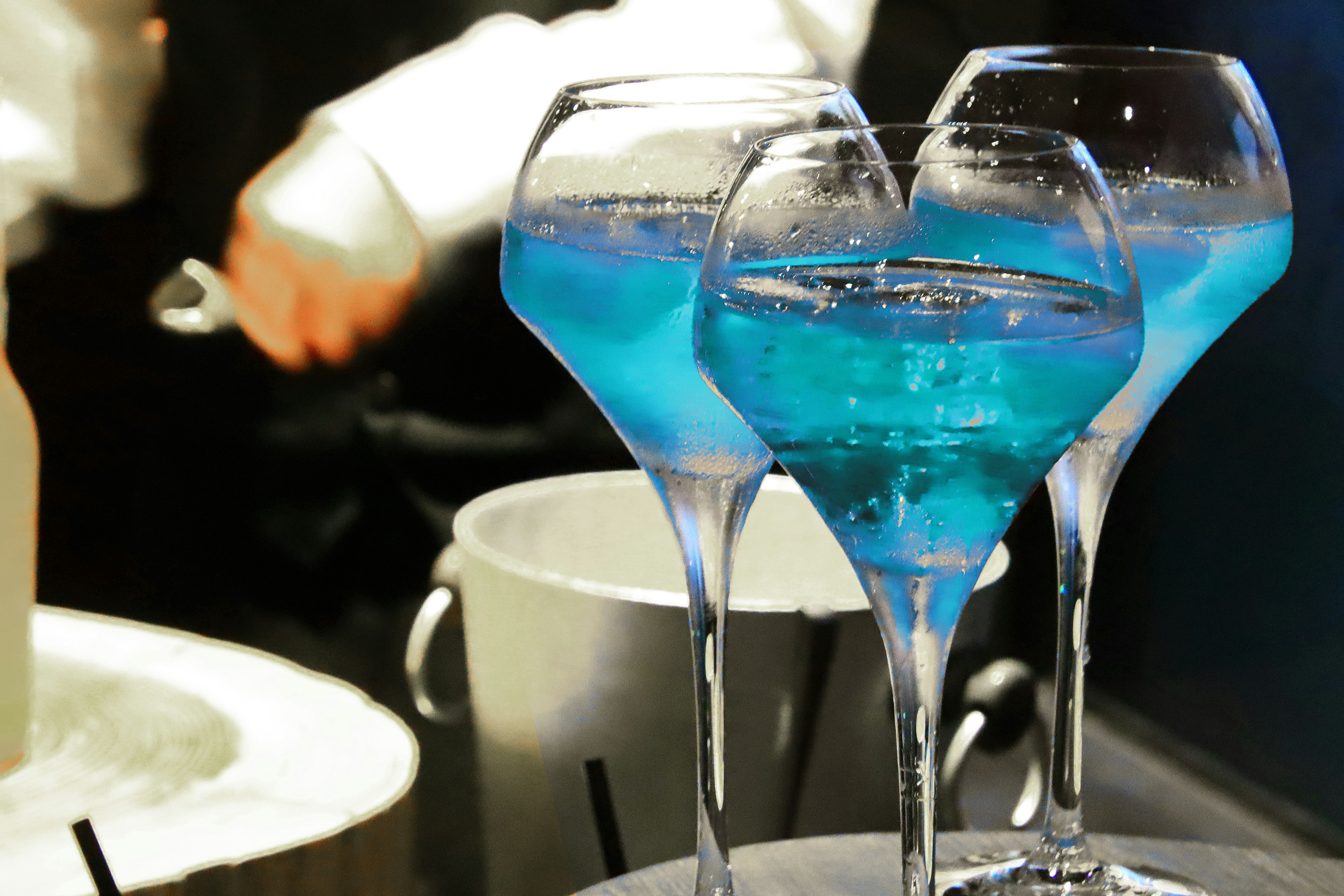 Three glasses of blue cocktails on a bar tray