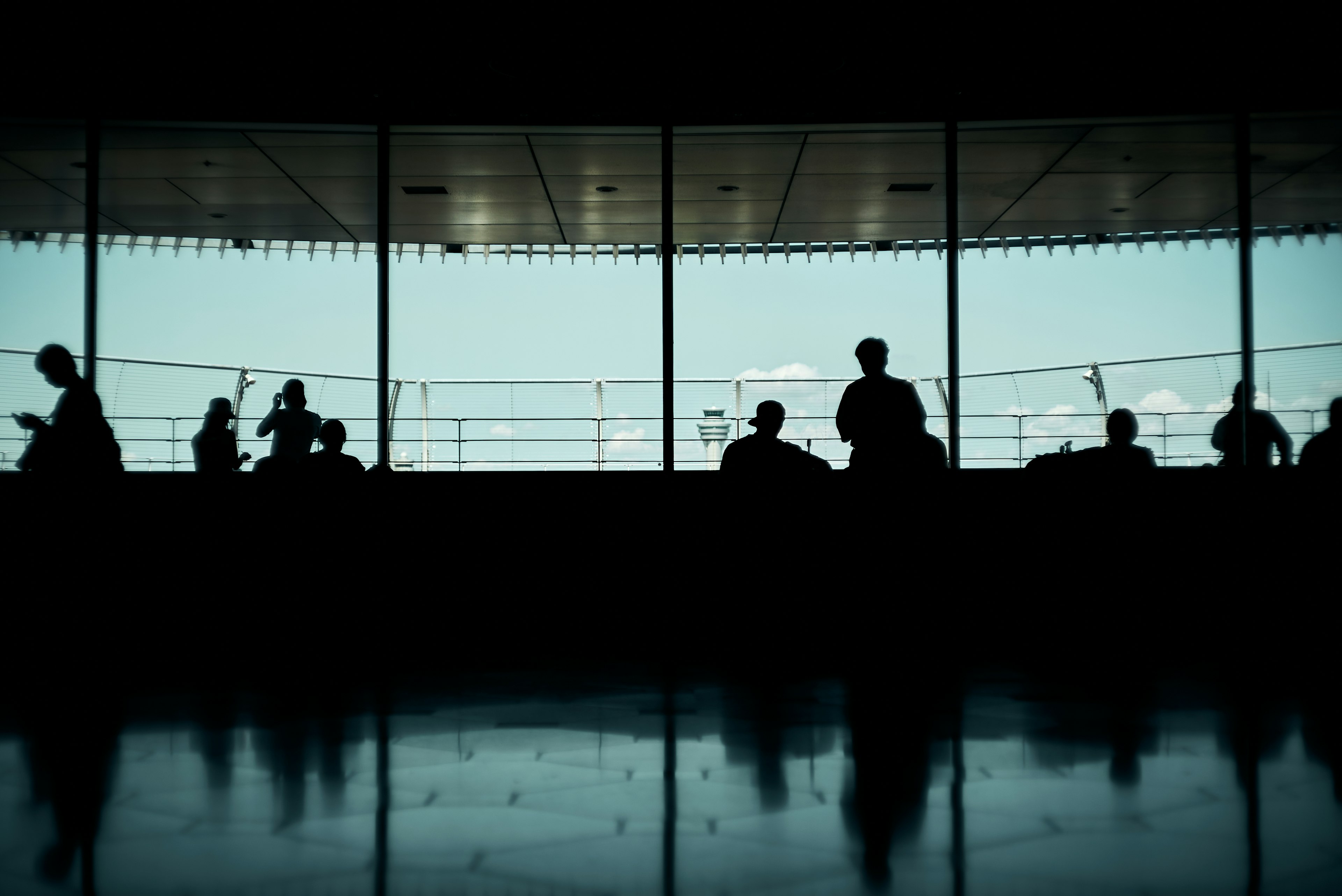 Silhouetten von Menschen durch die Flughafenfenster gesehen