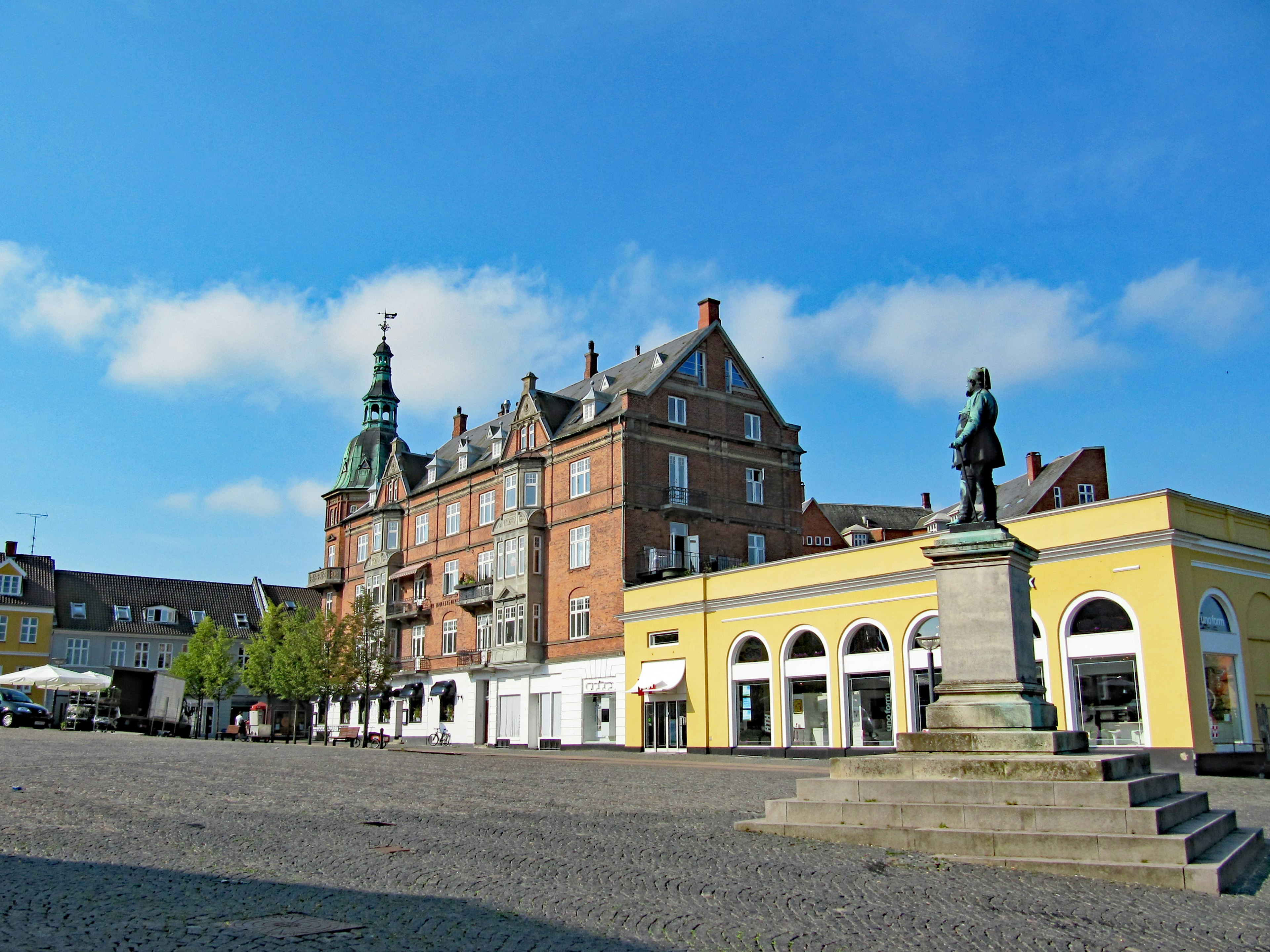 Place historique avec une statue et des bâtiments sous un ciel bleu