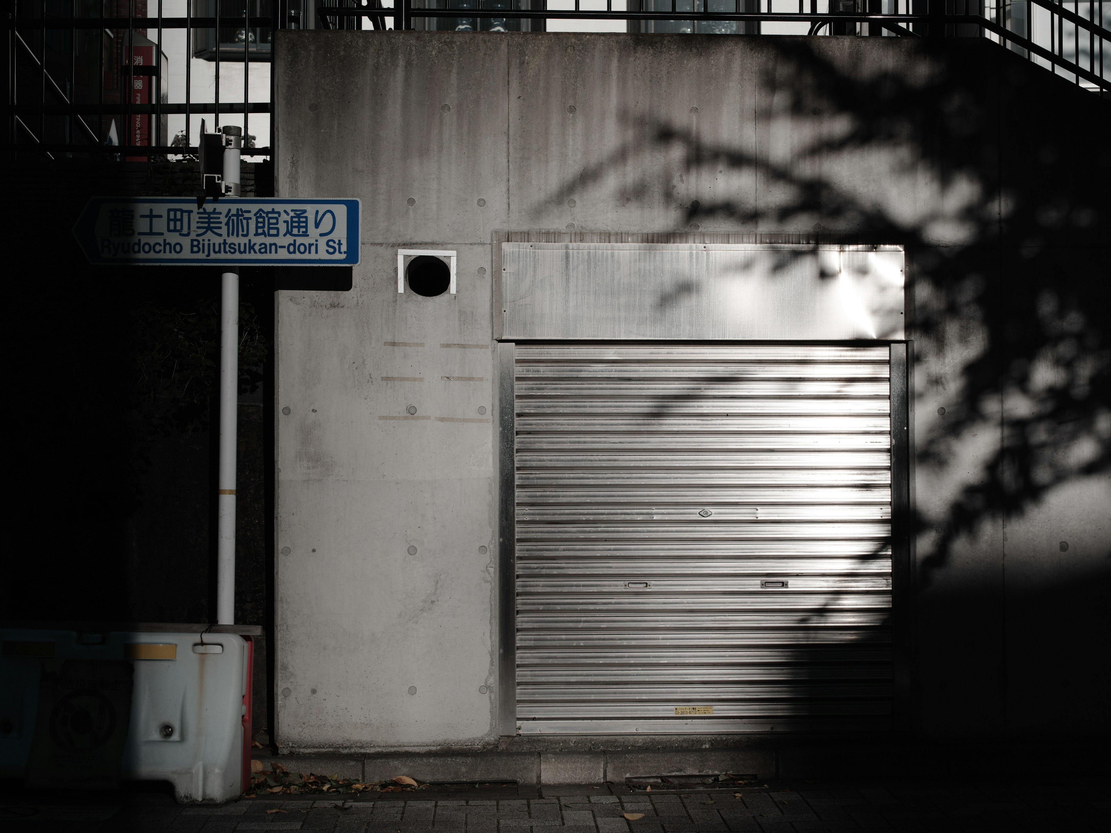 Scène urbaine avec un rideau métallique et un mur en béton dans un fond sombre