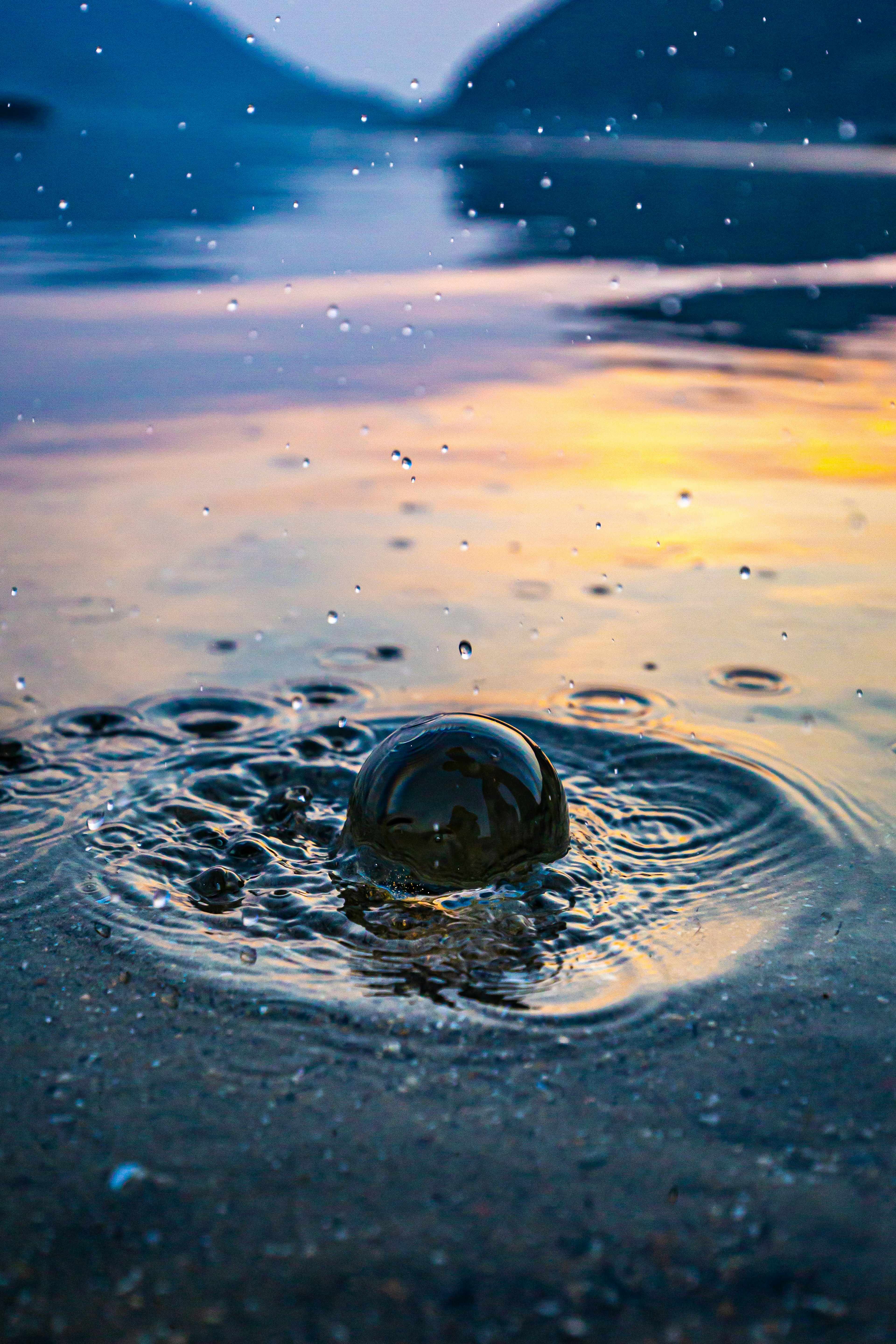 A spherical object on the water surface creating ripples with a beautiful sunset backdrop