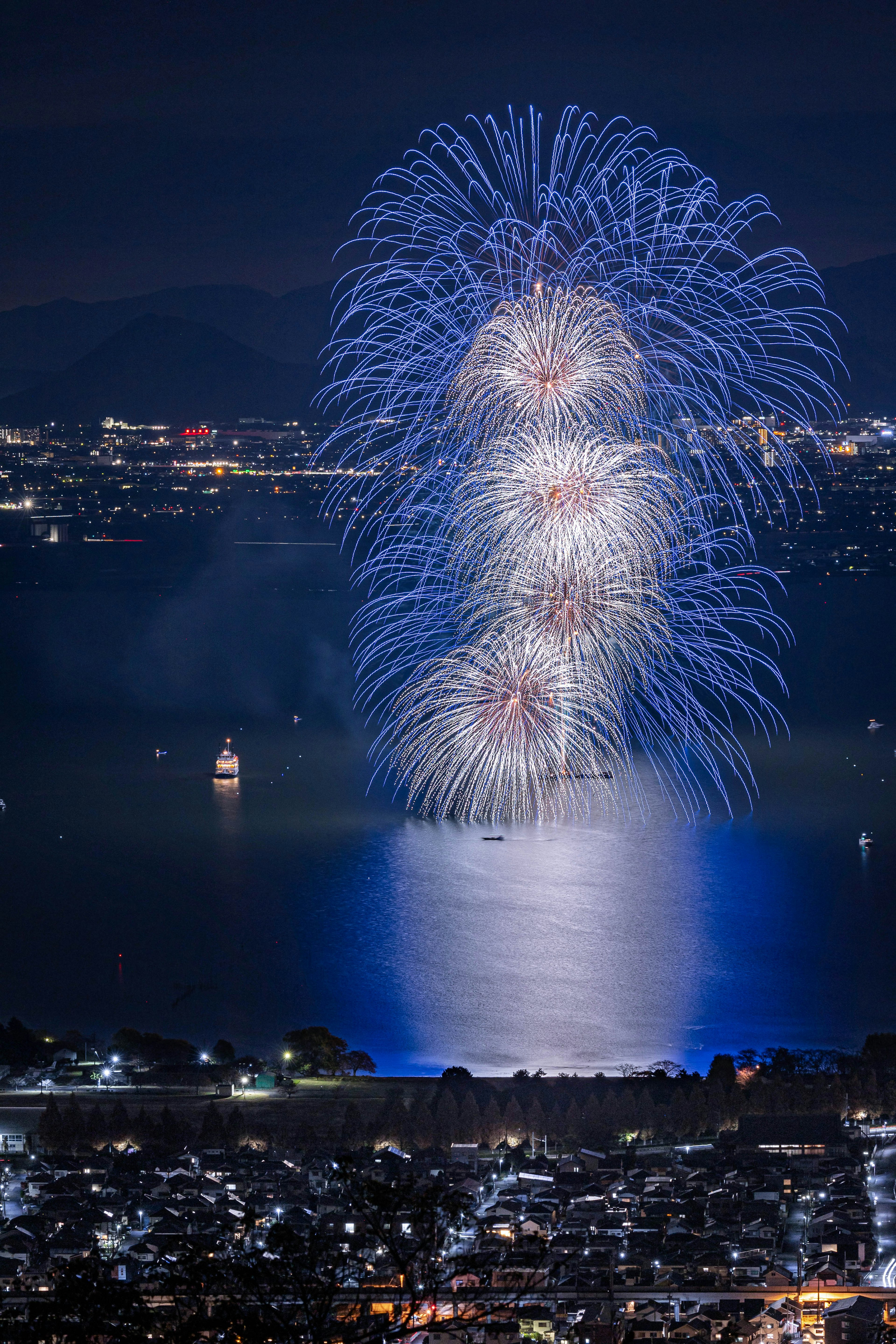 Beautiful display of blue fireworks reflecting on the lake at night