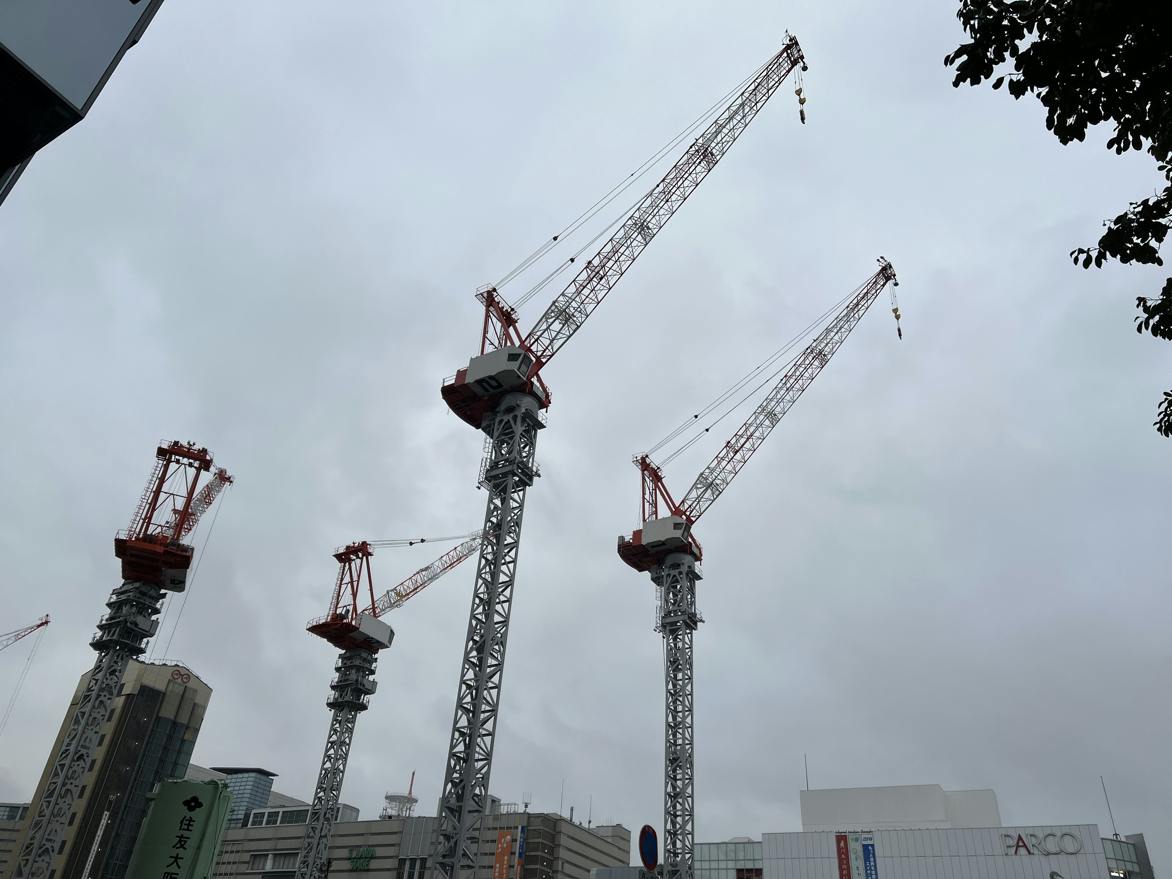 Gru di costruzione che svettano su un paesaggio urbano sotto un cielo nuvoloso