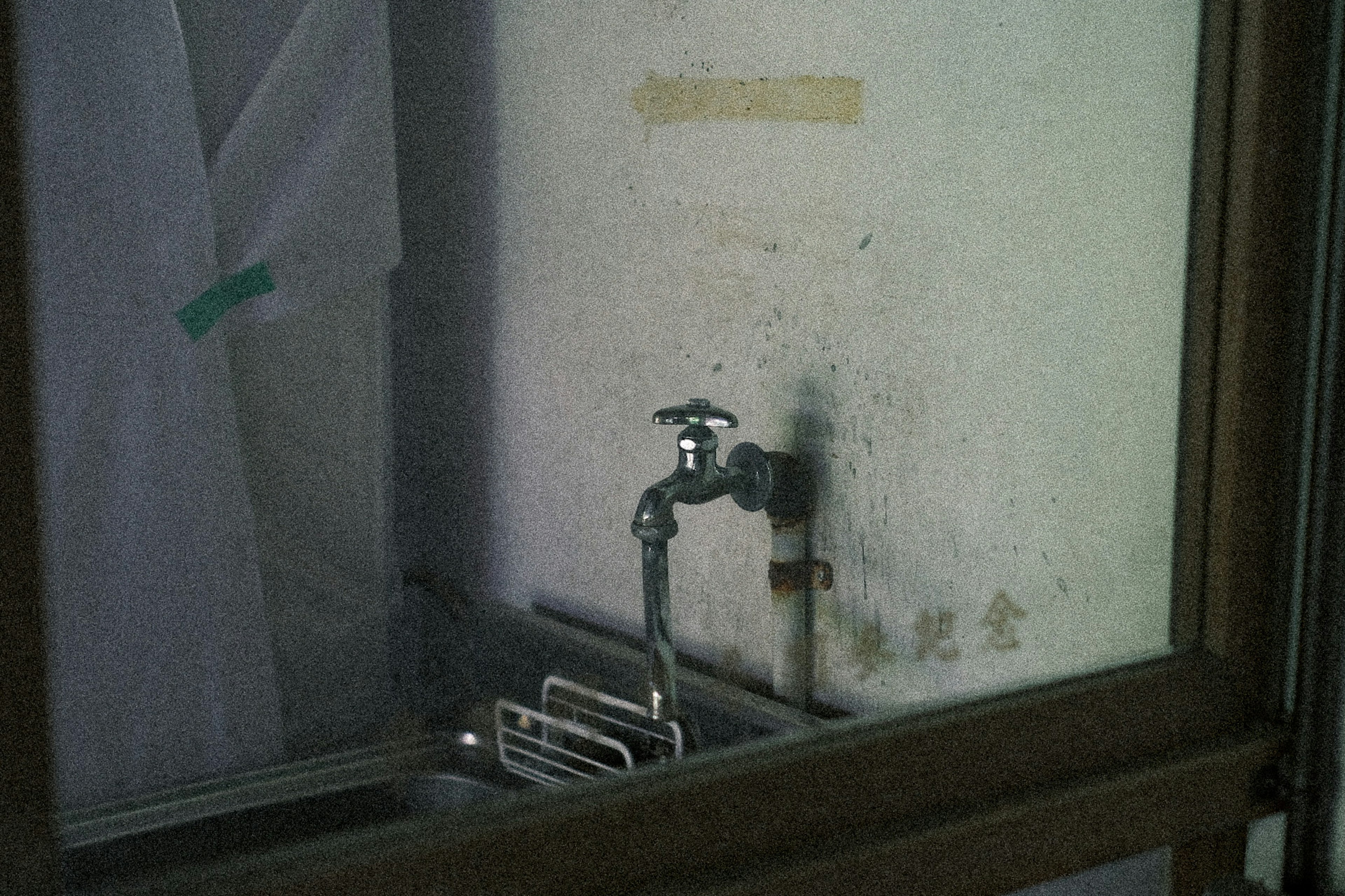 Image of an old sink and faucet seen through a window