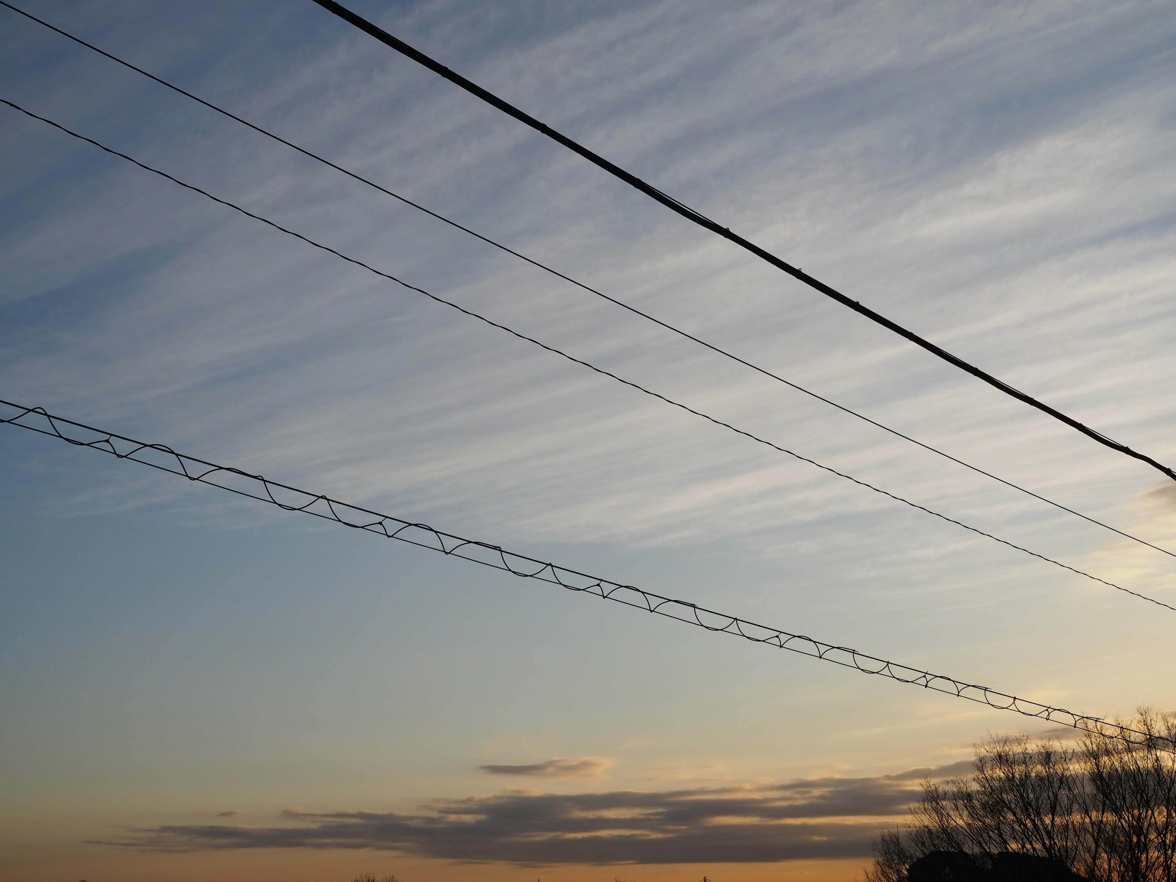 Silhouette de lignes électriques contre un ciel bleu avec des nuages légers