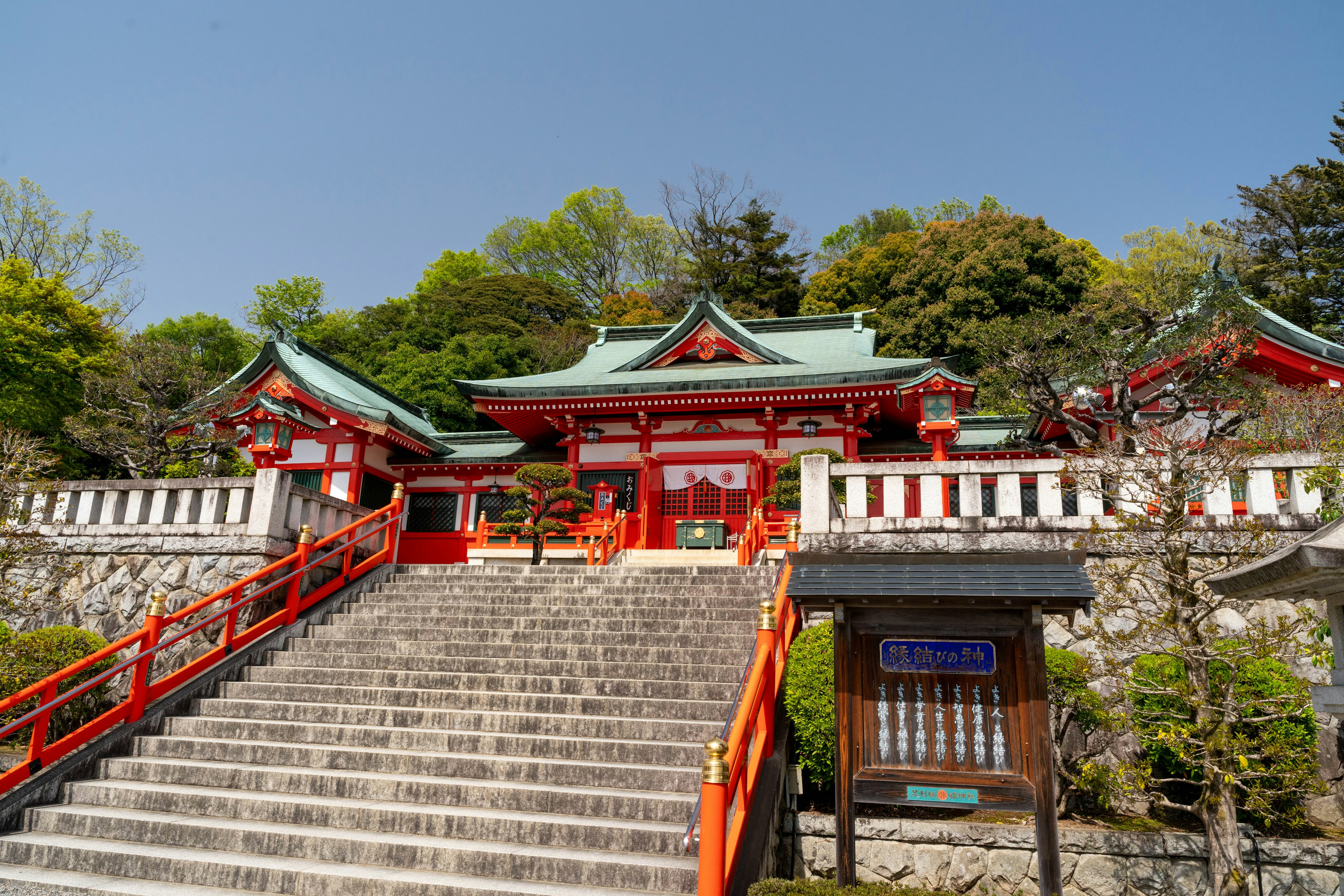 Stairs leading to a red shrine surrounded by greenery