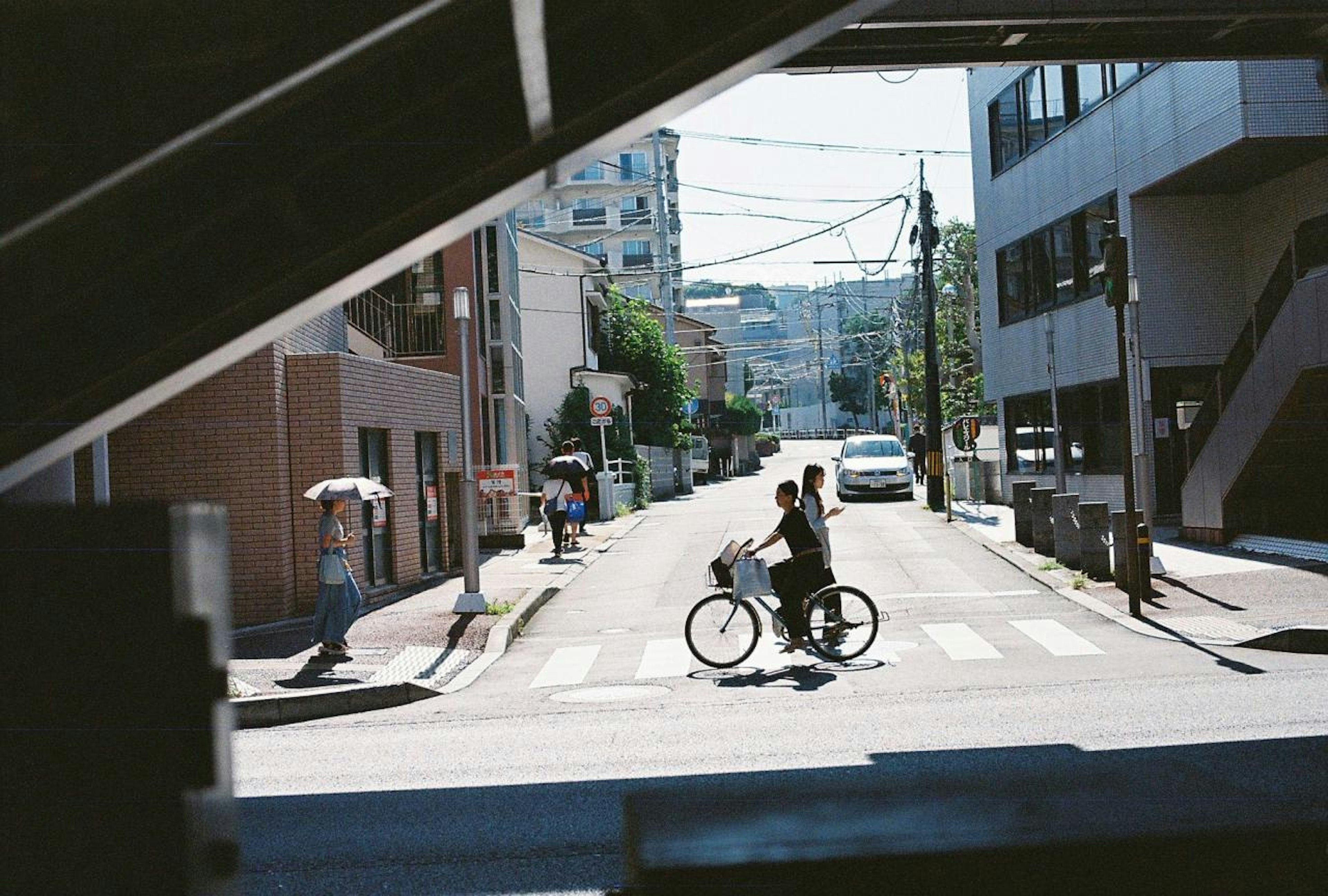 Two people on a bicycle crossing a street in an urban setting