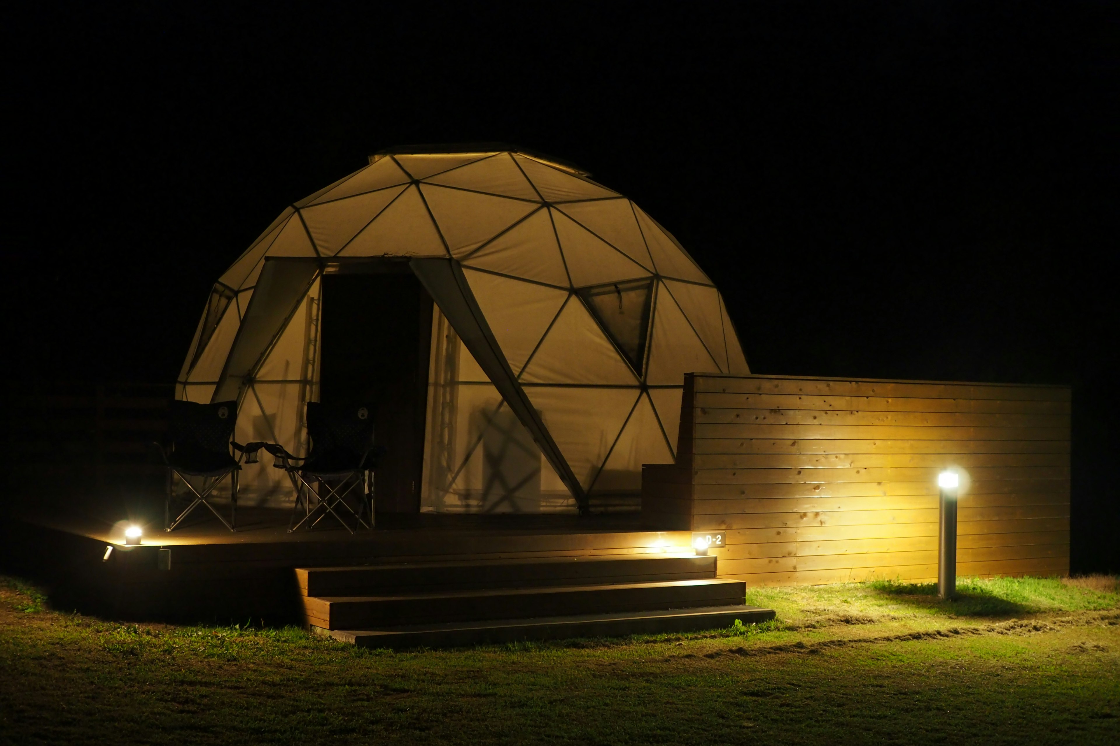 夜のドーム型テントとウッドデッキの風景