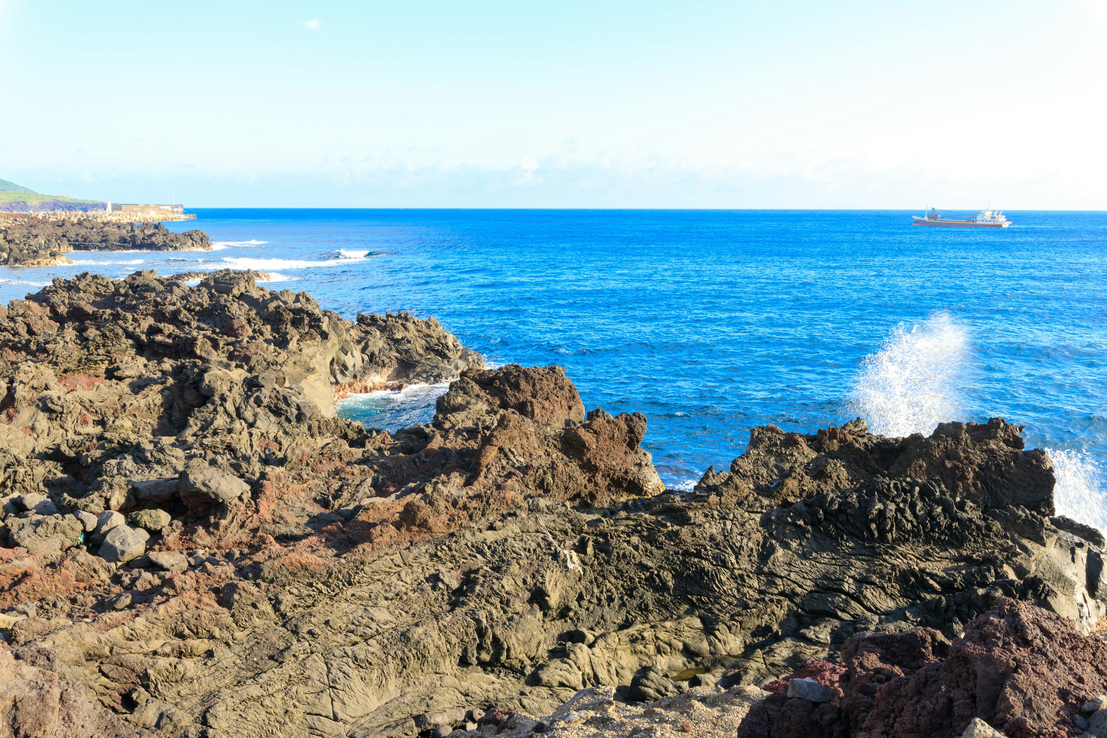 Costa rocciosa con onde oceaniche blu che si infrangono sulle rocce