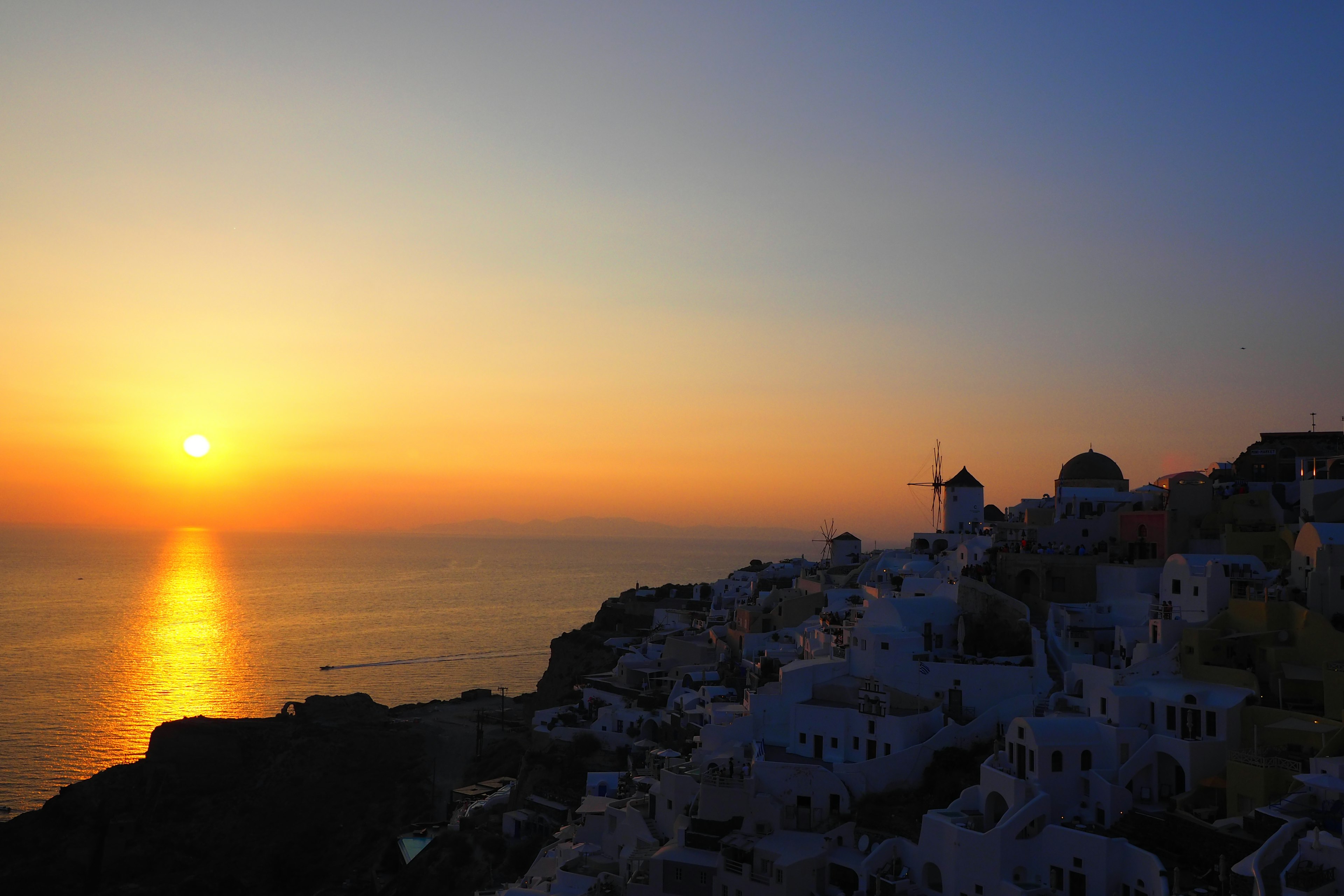 Pemandangan matahari terbenam yang menakjubkan di Santorini bangunan putih di lereng bukit