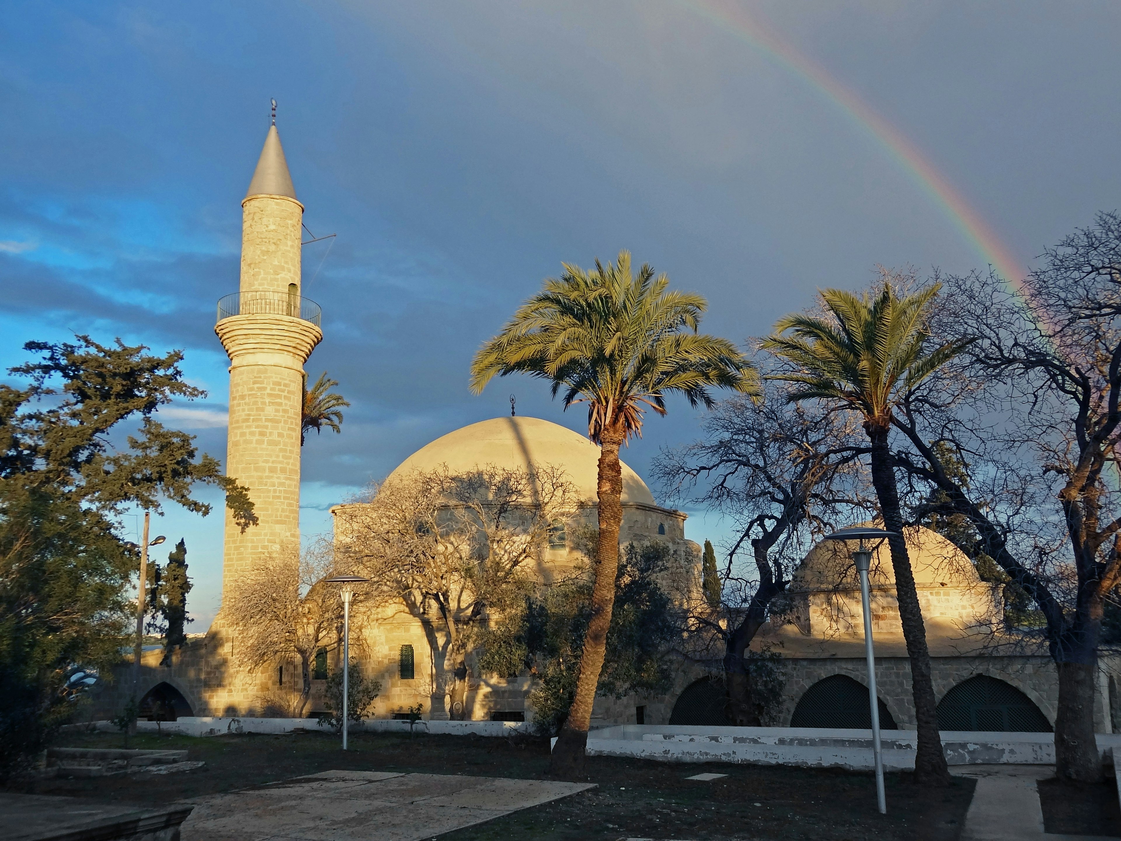 Historic mosque with a rainbow and palm trees