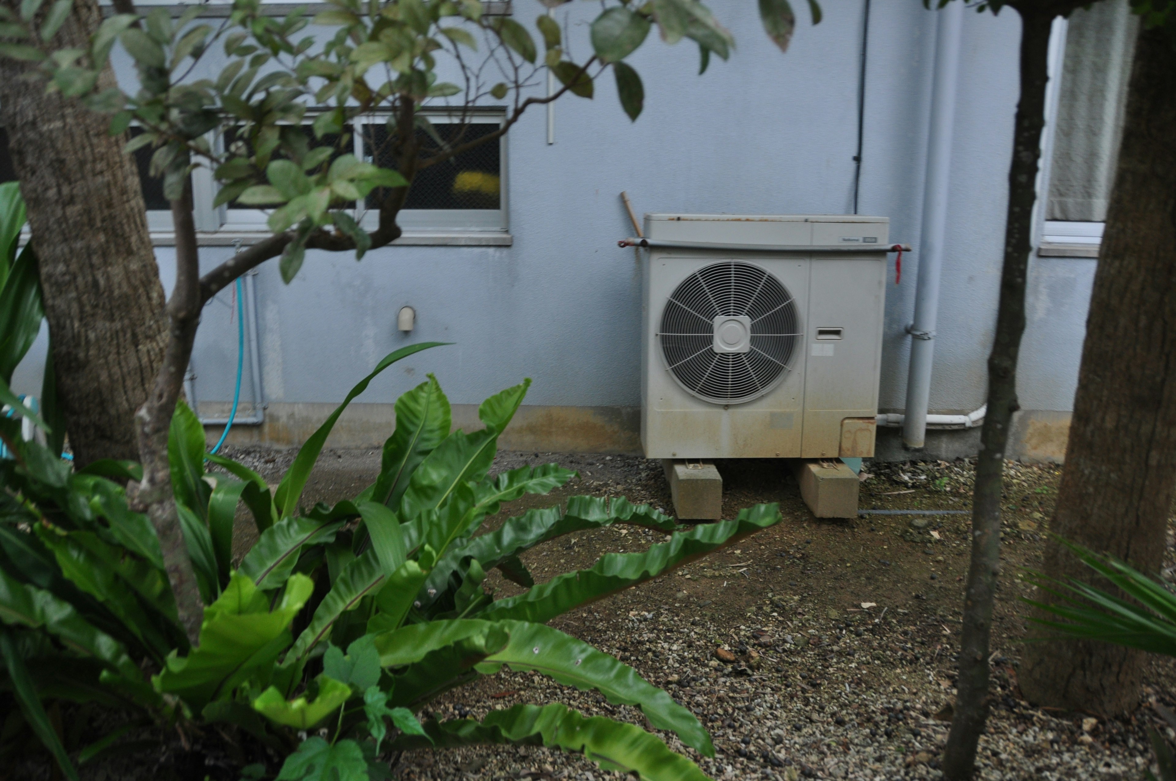 Air conditioning unit in a garden setting surrounded by greenery