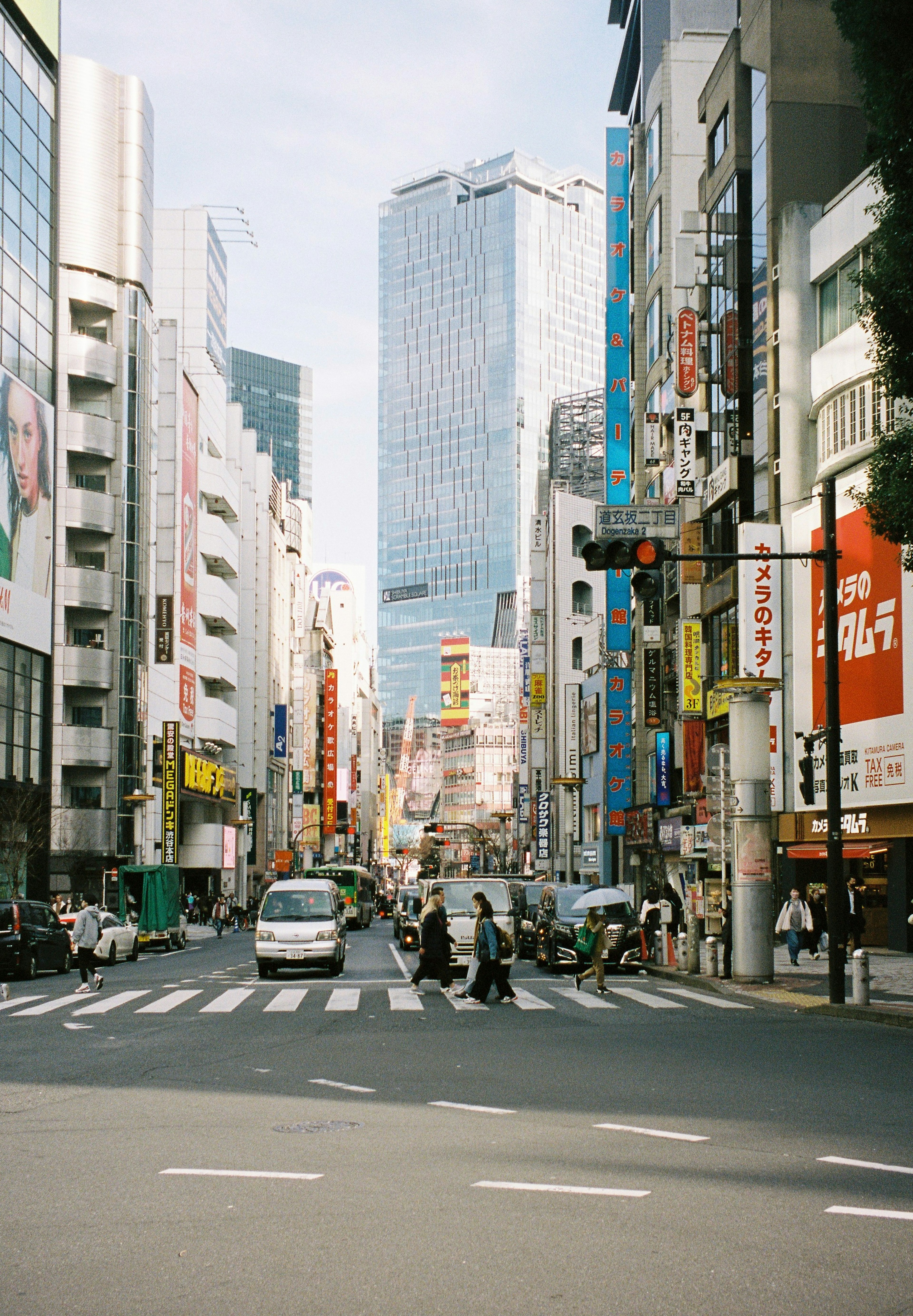 Busy street intersection with pedestrians and vehicles High-rise buildings in the background colorful signage