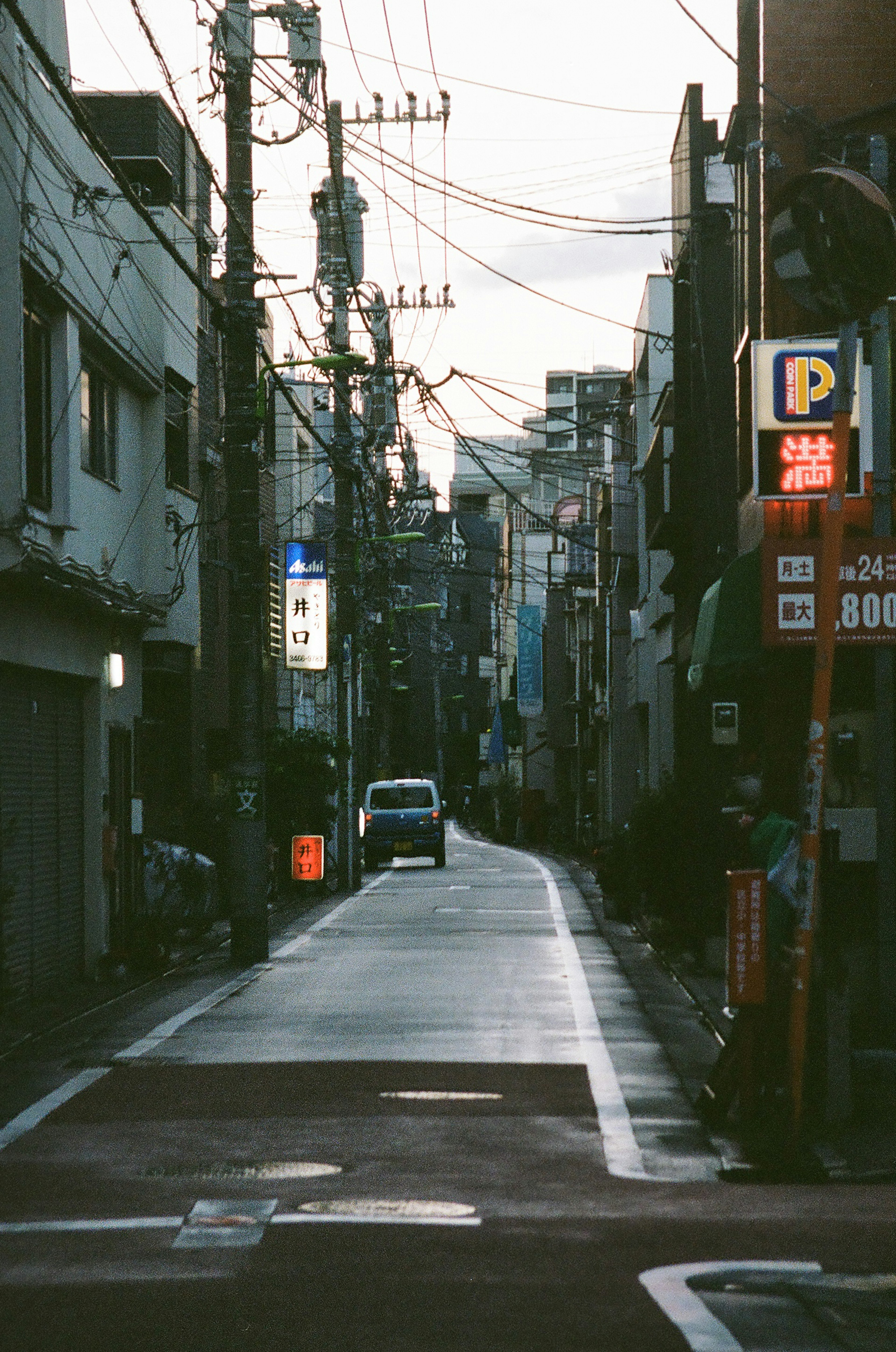 Scena di strada tranquilla a Tokyo al crepuscolo Strada stretta con un'auto in transito e linee elettriche