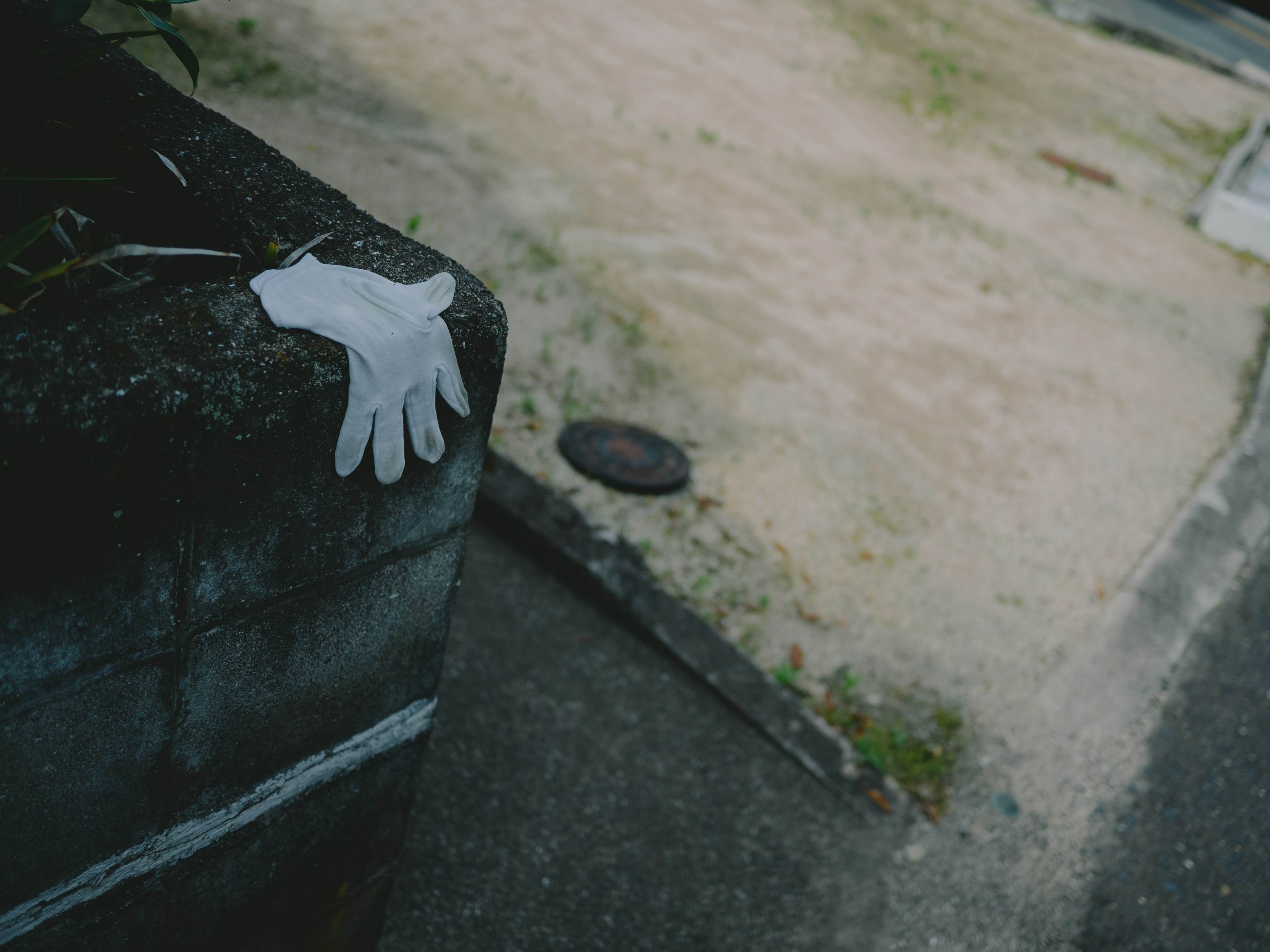 A white glove resting on a concrete wall in a deserted area