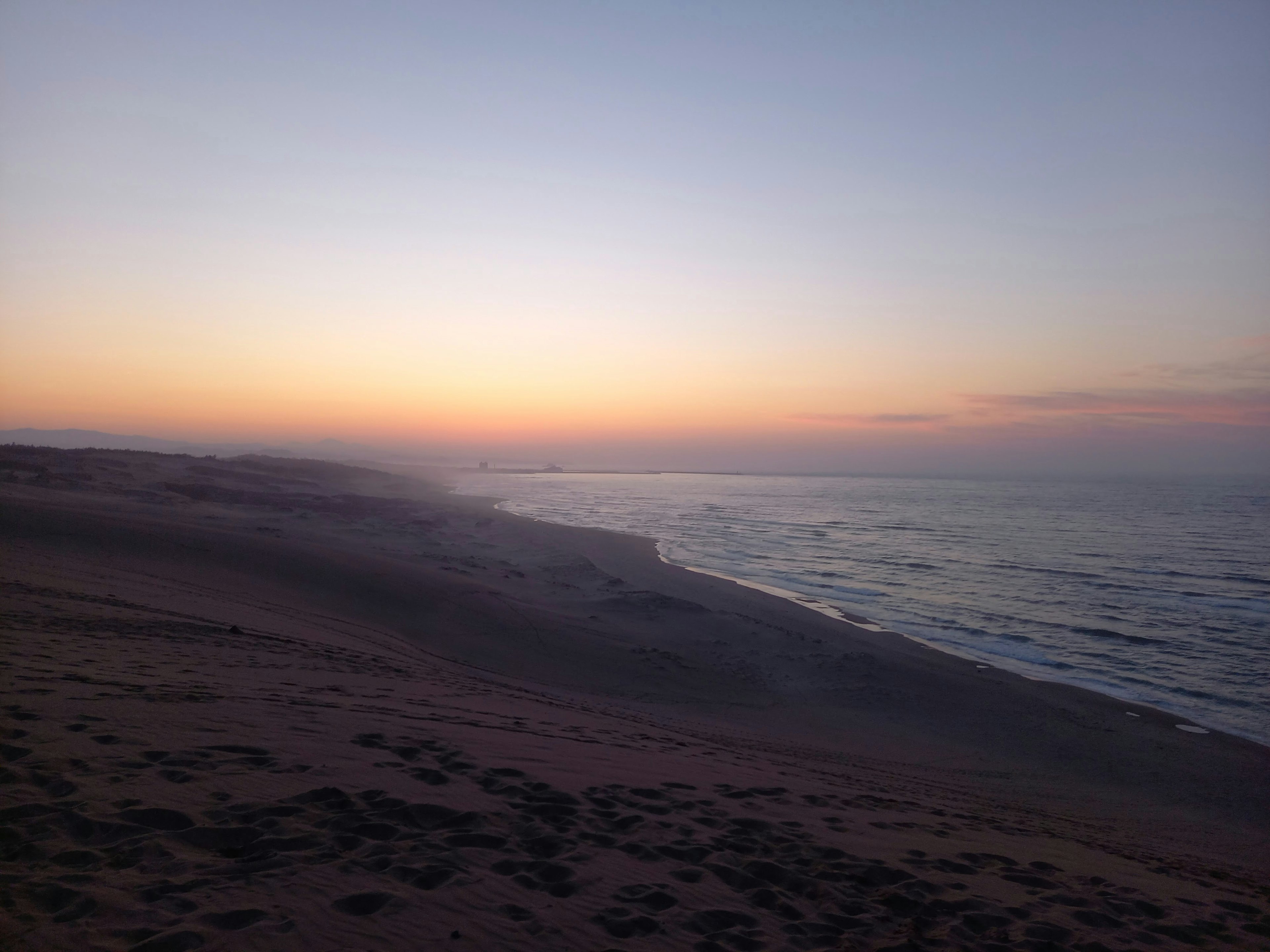 Sonnenuntergangsansicht der Küste mit Sandstrand und Meereswellen