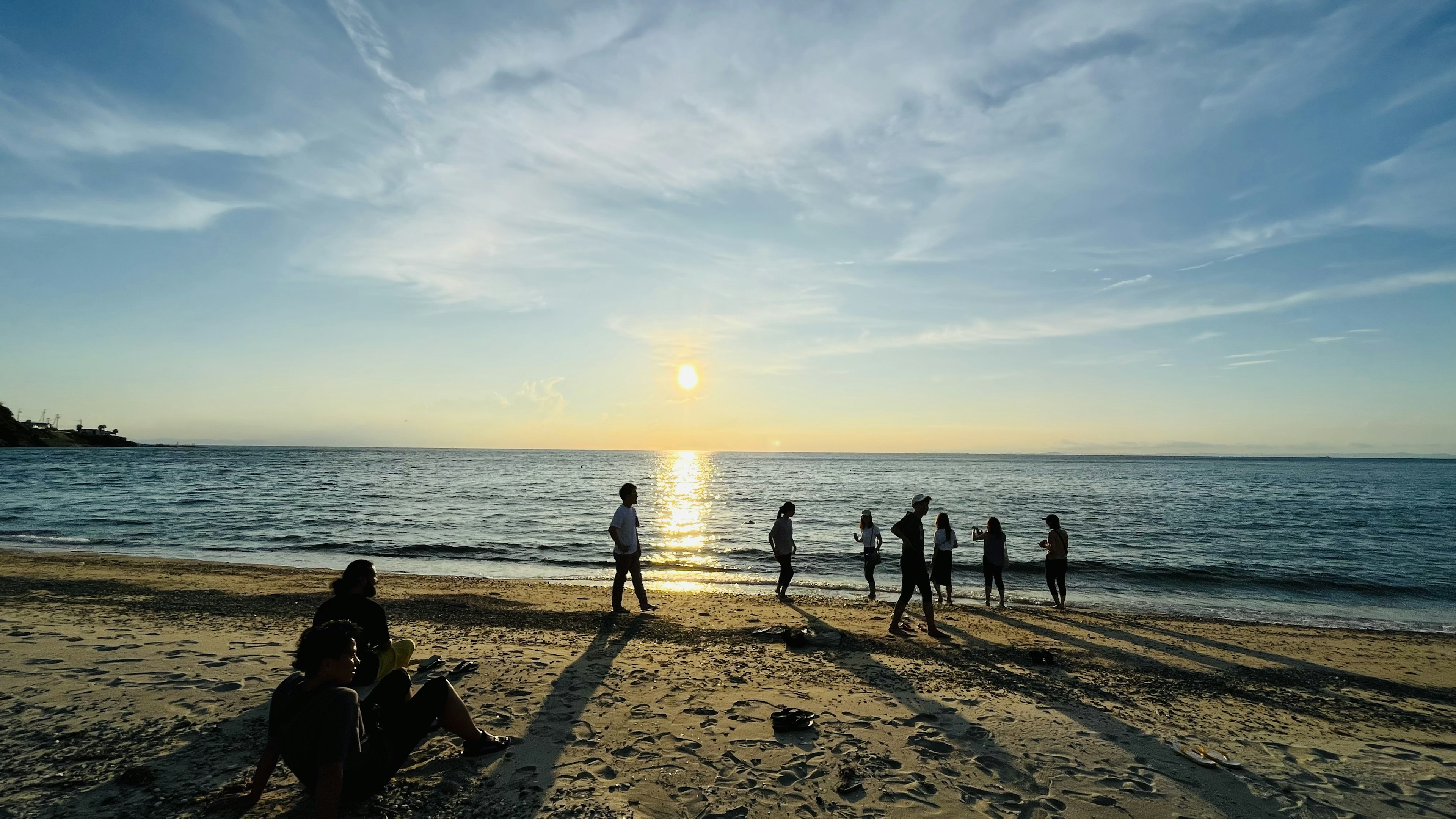 ビーチで夕日を背景に遊ぶ人々のシルエット