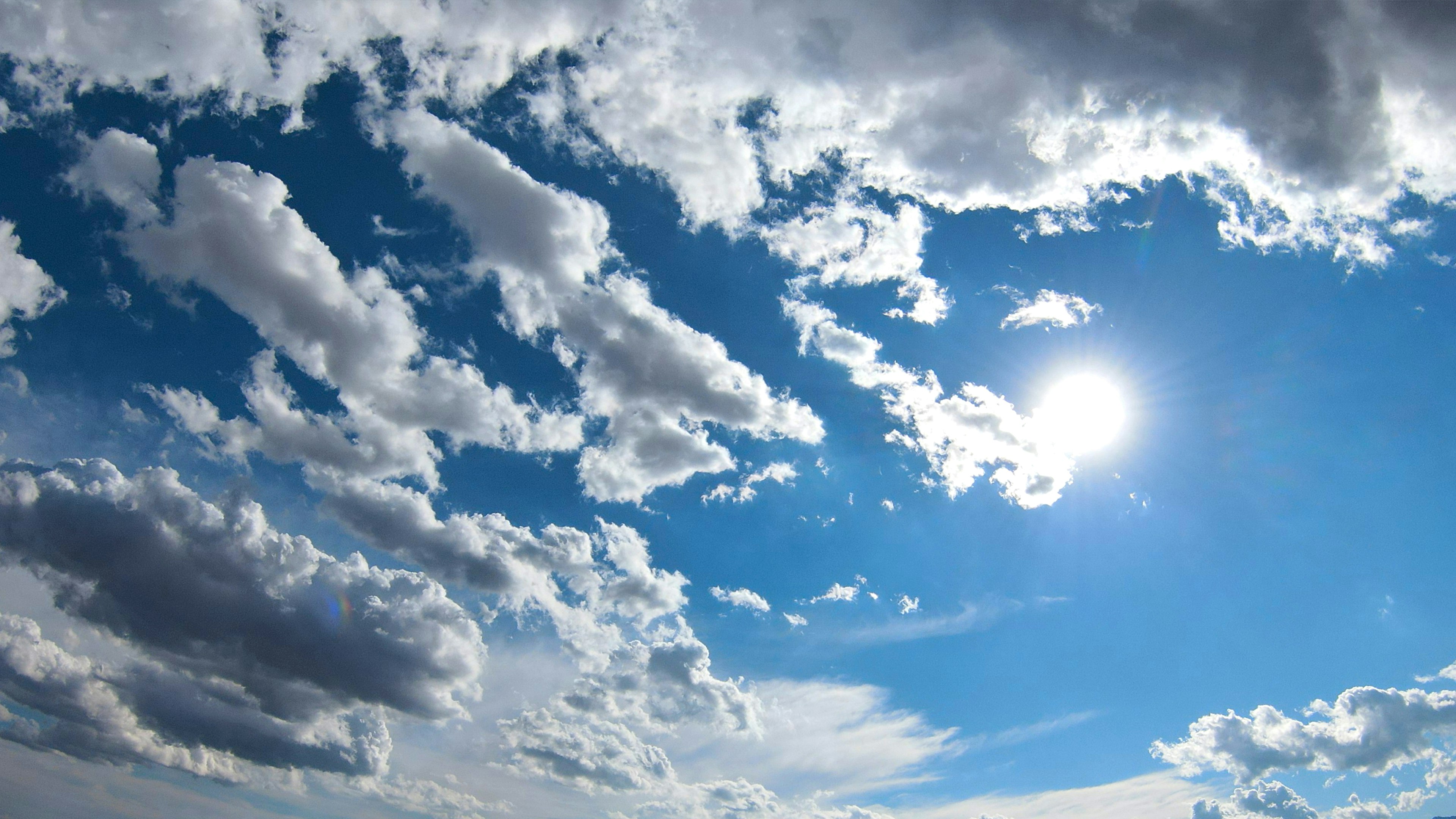 Vibrant blue sky with white clouds and shining sun